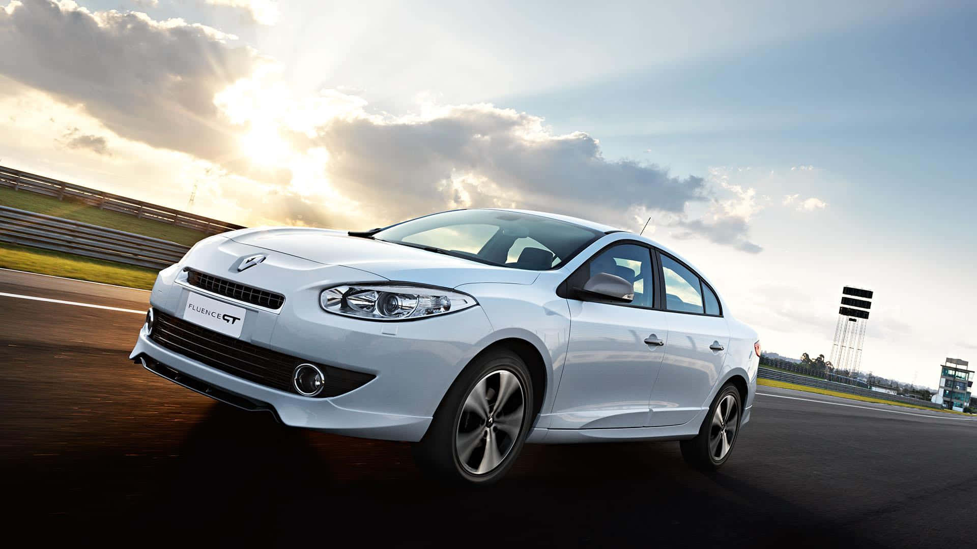 Renault Fluence 桌布 壁紙 — 一輛時尚的銀色雷諾Fluence GT在戲劇性的金色日落天空下於賽道上飛馳。