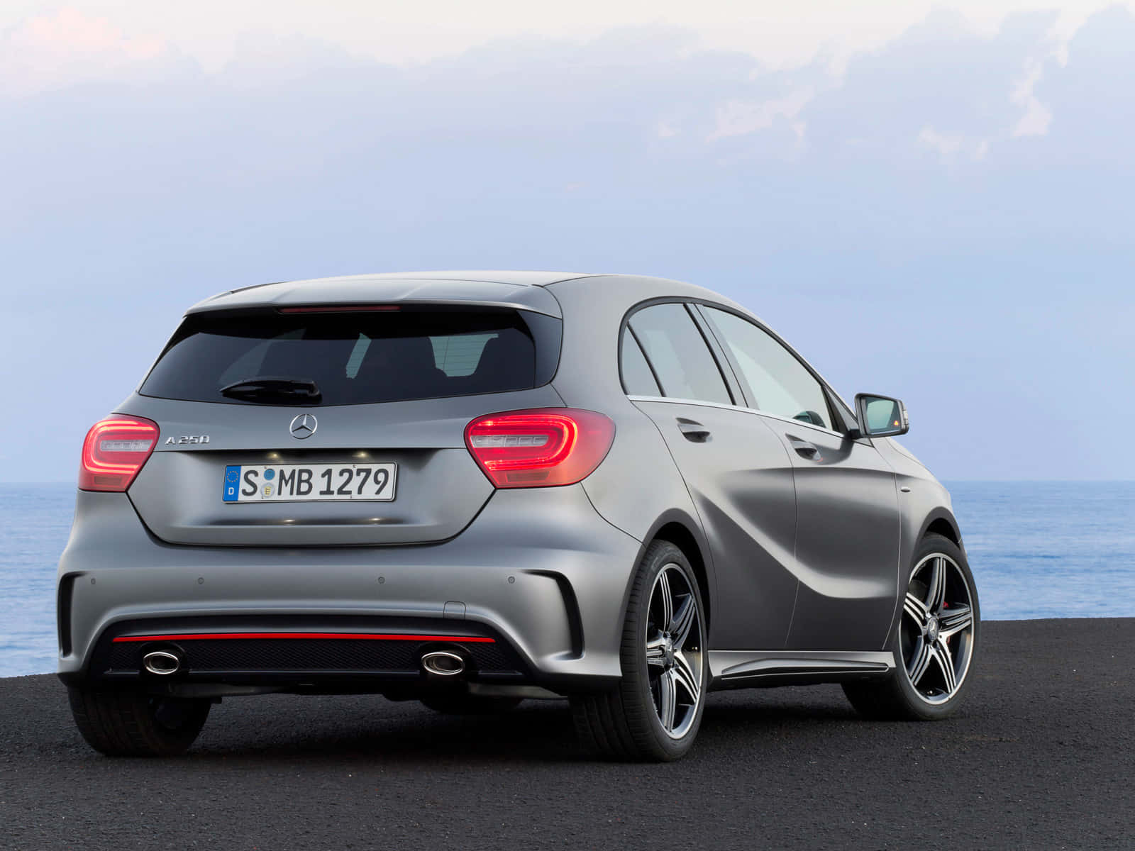 Mercedes Benz A-class 桌布 壁紙 — 一輛時尚的銀色 Mercedes A45 AMG 停在黑暗的路面上，背景是海洋和陰天。