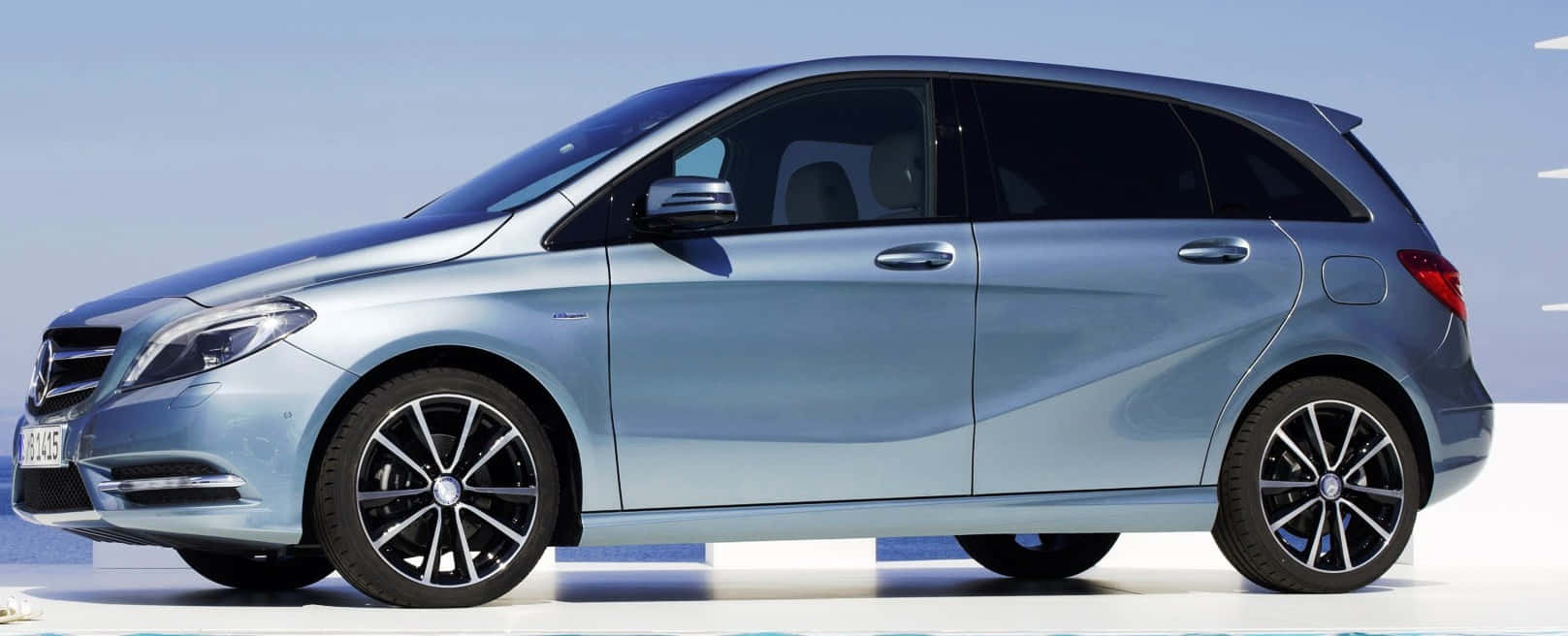 Mercedes Benz B-class 桌布 壁紙 — 一輛時尚的銀色 Mercedes-Benz B-Class 旅行車在明亮的日光下，在極簡的白色平台上閃閃發光。