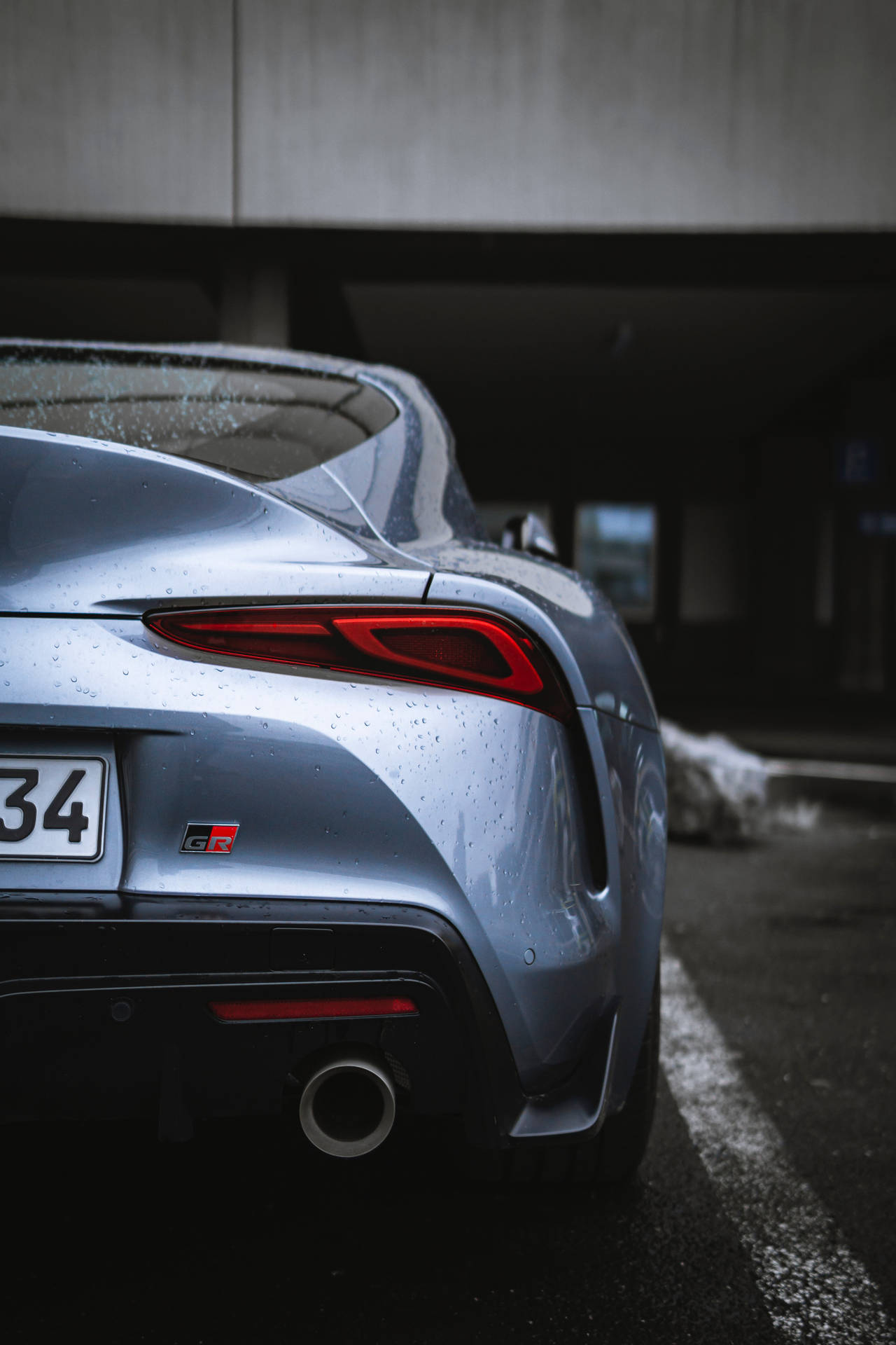 銀色跑車，紅色尾燈，停泊在濕滑的混凝土天橋下。 — Toyota Supra 壁紙