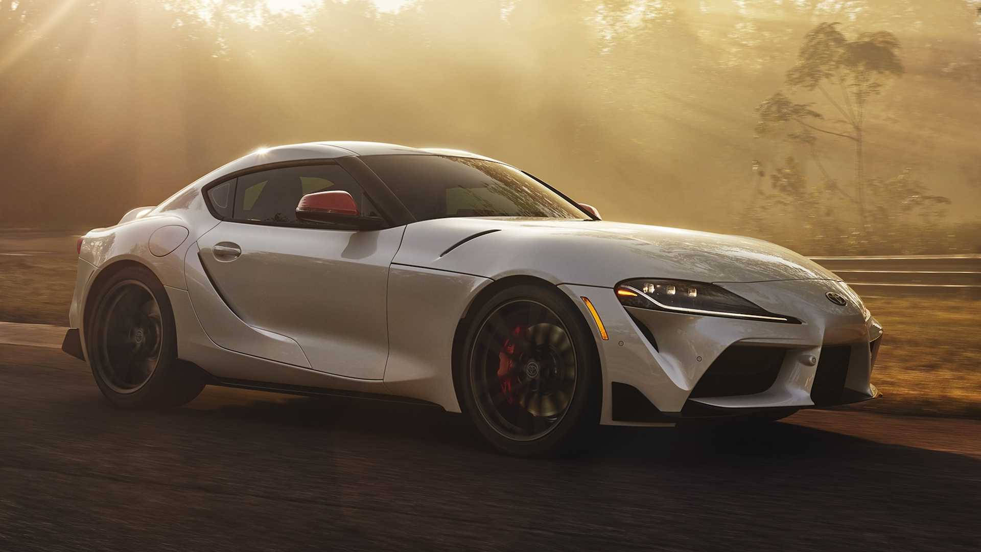 日落時分，銀色跑車在陽光普照的林間道路上飛馳。 — Toyota Supra 壁紙