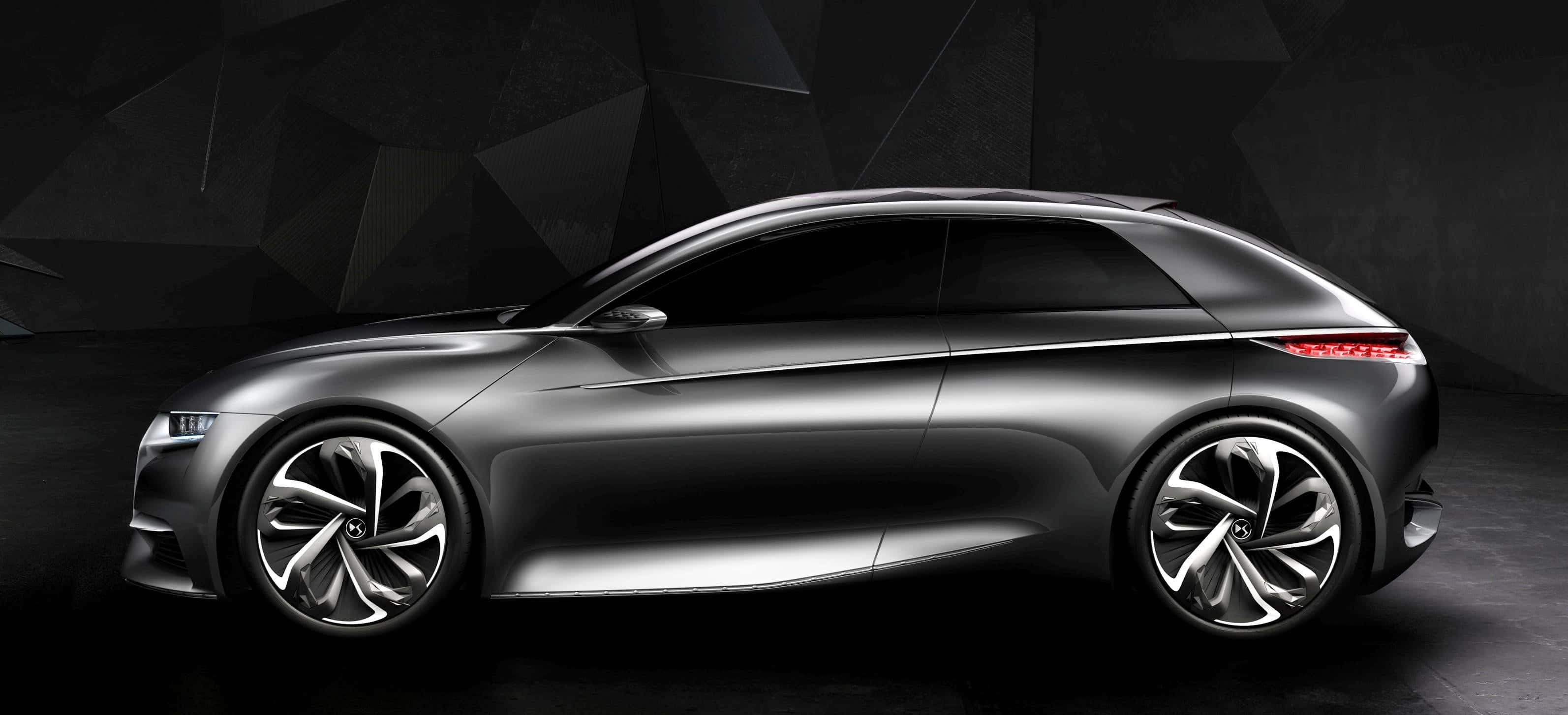 Citroen Divine Ds Concept 桌布 壁紙 — 一輛時尚的銀色未來感旅行車，帶有發光的紅色尾燈，停在深色幾何牆前。