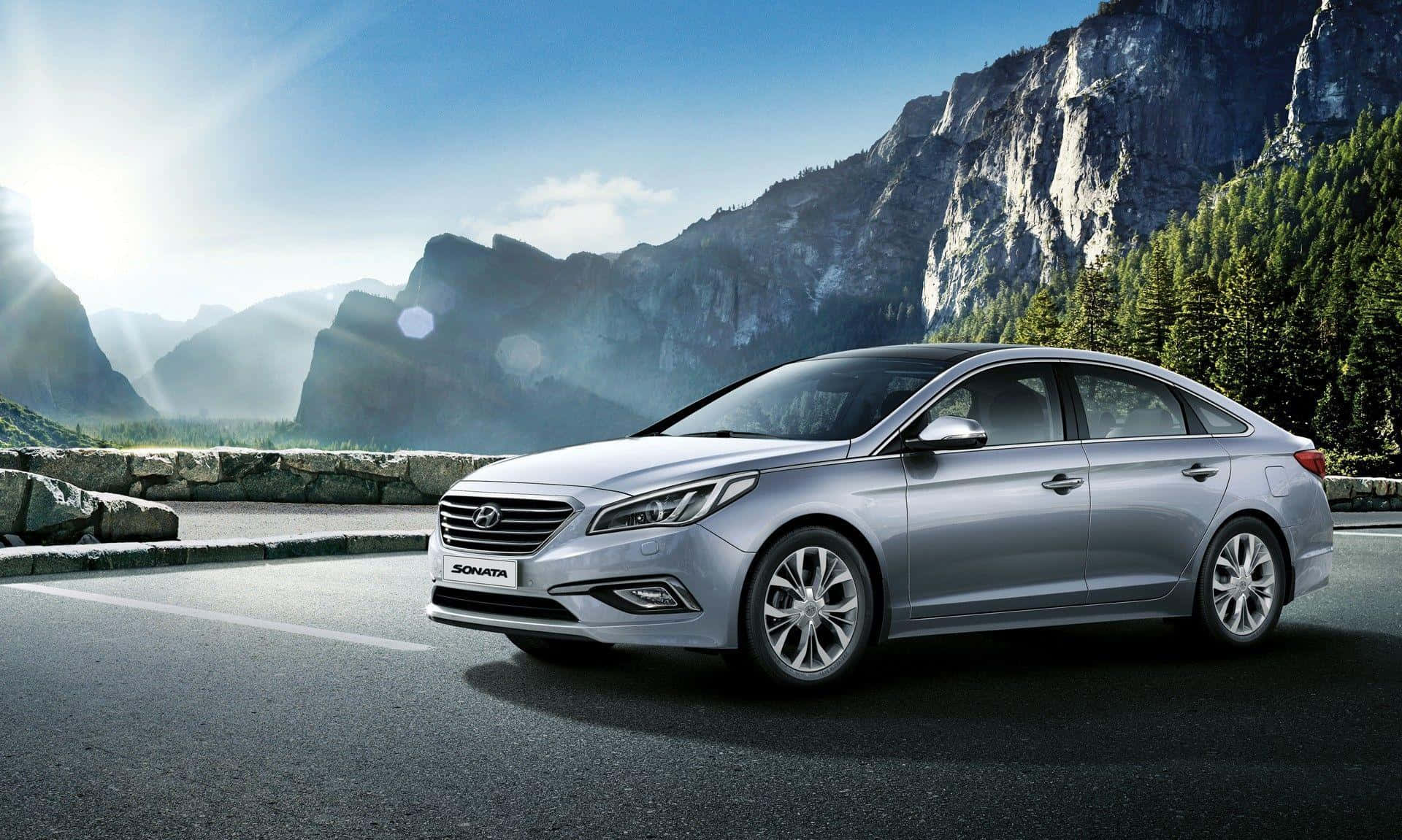 Hyundai Sonata 桌布 壁紙 — 一輛時尚的銀色現代Sonata轎車停泊在山路上，背景有太陽光暈和崎嶇的懸崖。