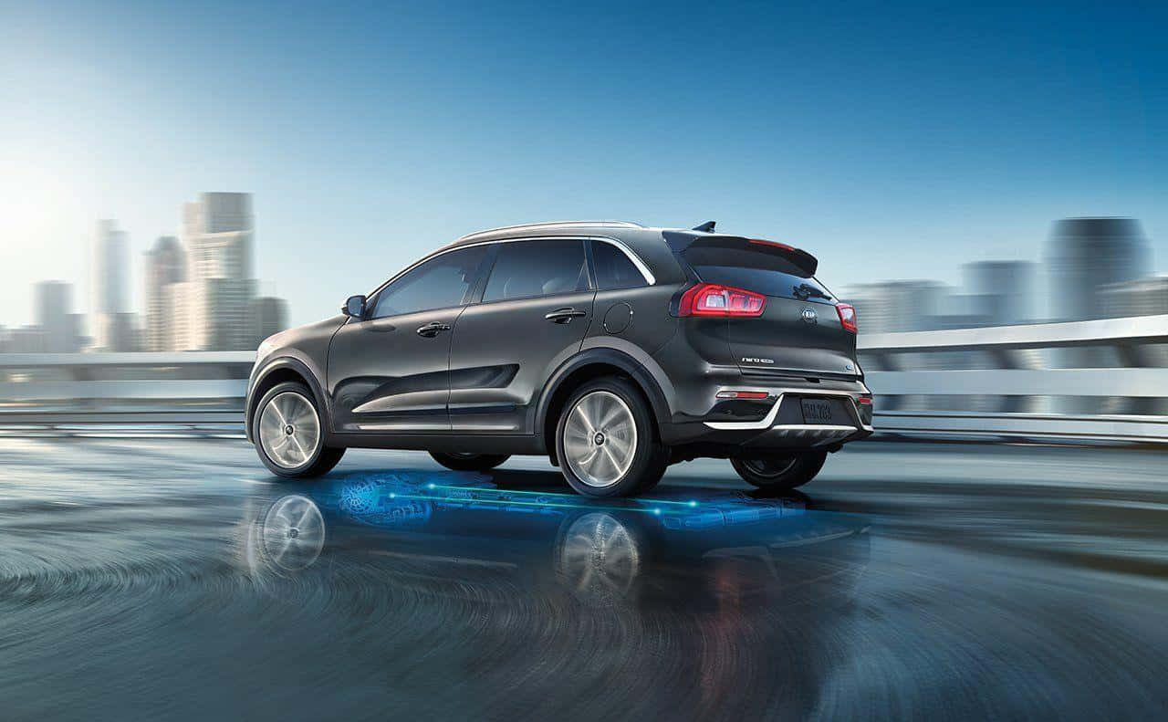 Kia Niro 桌布 壁紙 — 一輛時尚灰色SUV在潮濕的城市橋上高速行駛，模糊的摩天大樓在晴朗藍天下。