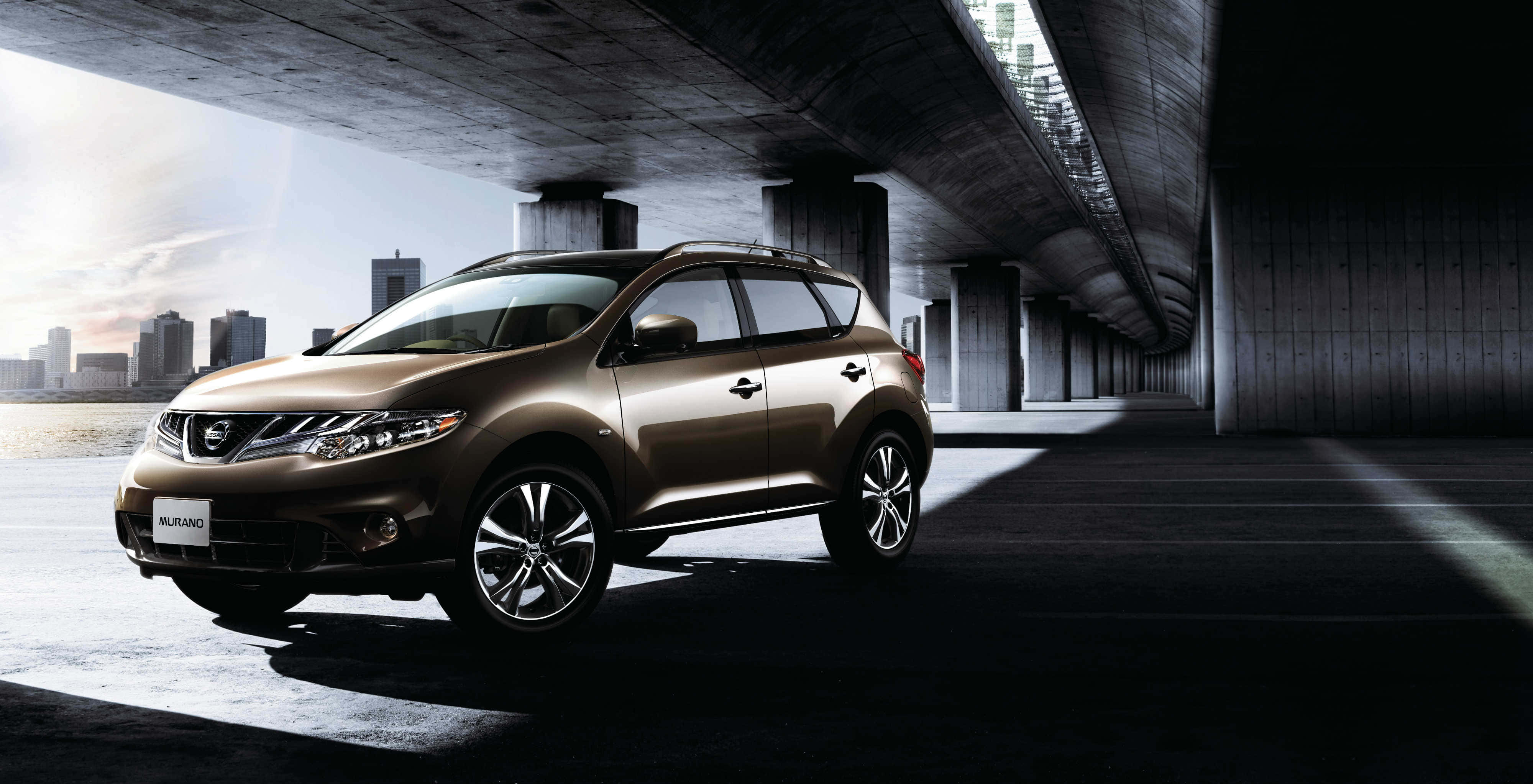 Nissan Murano 桌布 壁紙 — 一輛時尚青銅色日產Murano SUV停泊在現代混凝土天橋下，背景是城市天際線。