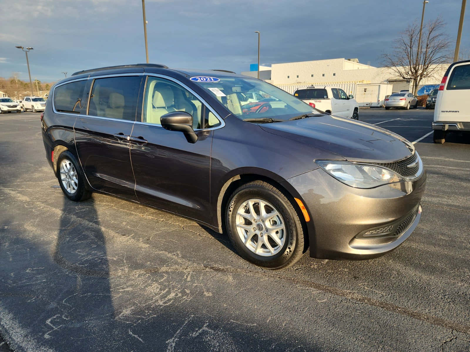 Chrysler Voyager 桌布 壁紙 — 一輛時尚深灰色2021年克萊斯勒Pacifica小型貨車停放在停車場，天空多雲，附近有其他車輛。