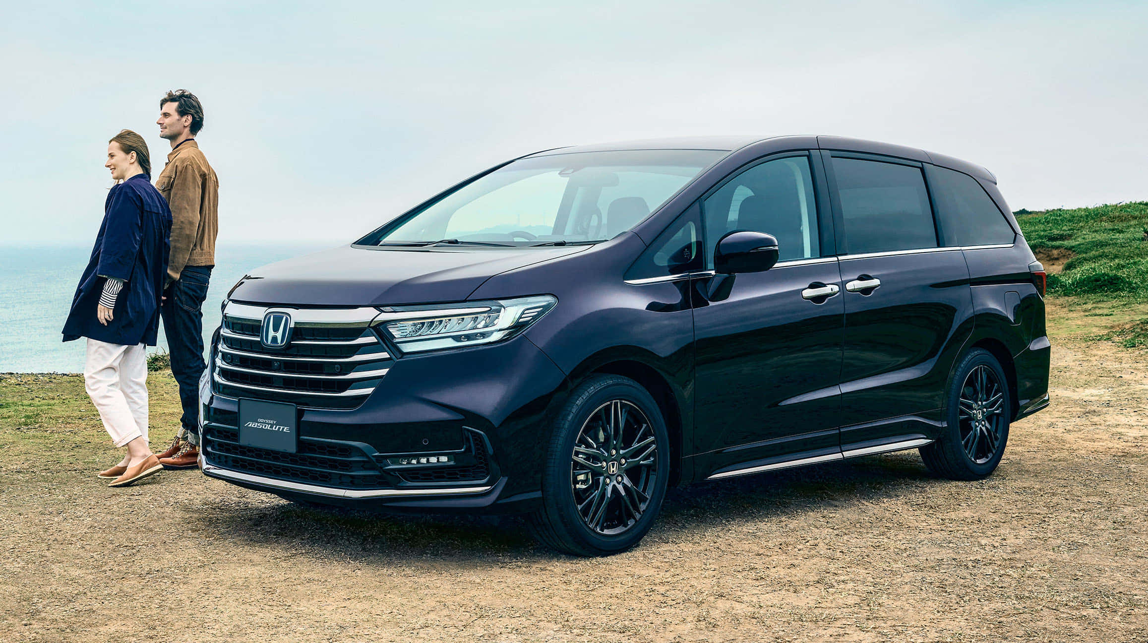 Honda Odyssey 桌布 壁紙 — 一輛時尚深藍色本田Odyssey小型貨車停泊在海岸懸崖上，一對情侶站在旁邊俯瞰海洋。