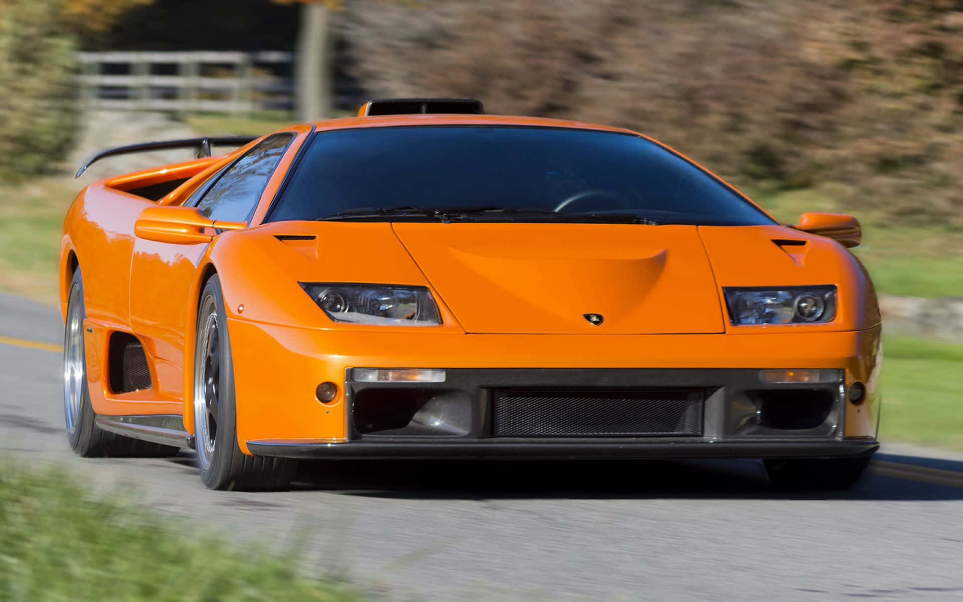 Lamborghini Diablo 桌布 壁紙 — 一輛鮮橙色的藍寶堅尼 Diablo 在蜿蜒的道路上疾馳，背景是模糊的綠意。