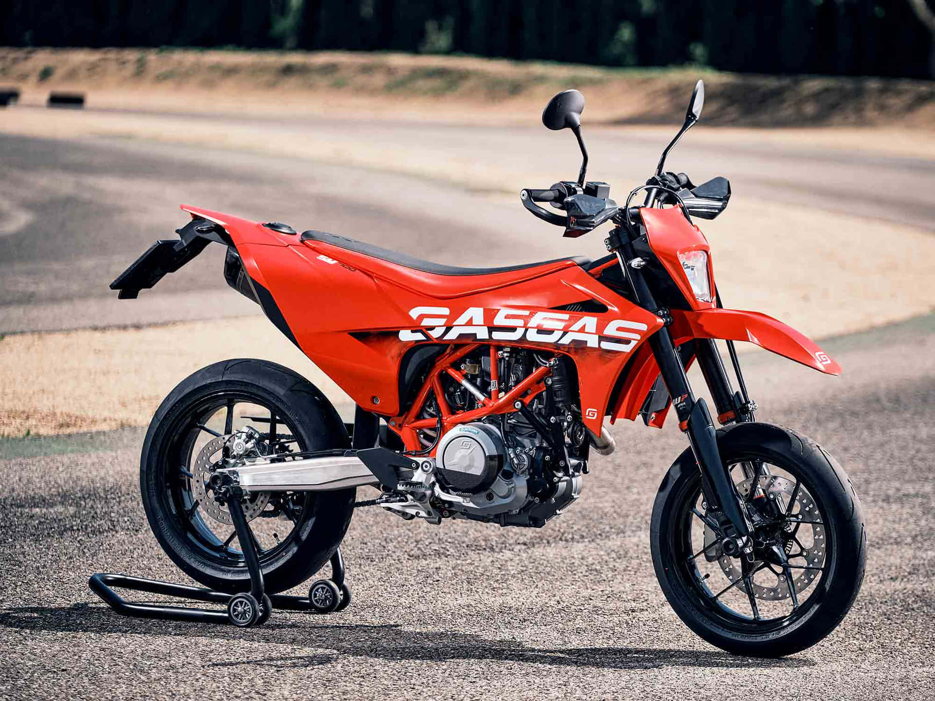  壁紙 — 一輛鮮橙色的KTM 350 EXC-F越野摩托車停在碎石路上，背景是樹木茂密的山丘。