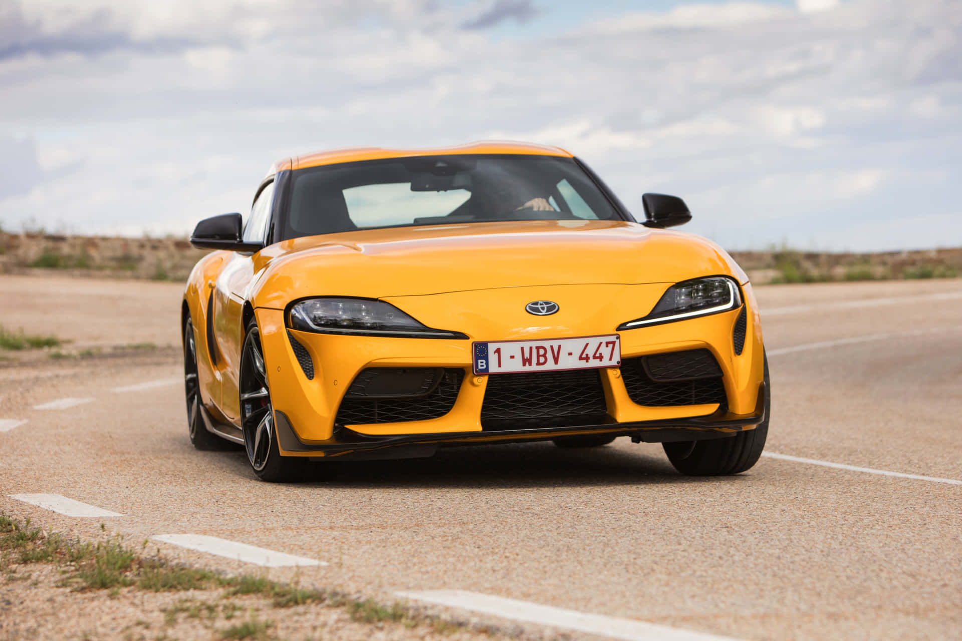 沙漠公路上多雲天空下的黃色豐田Supra。 — Toyota Supra 壁紙