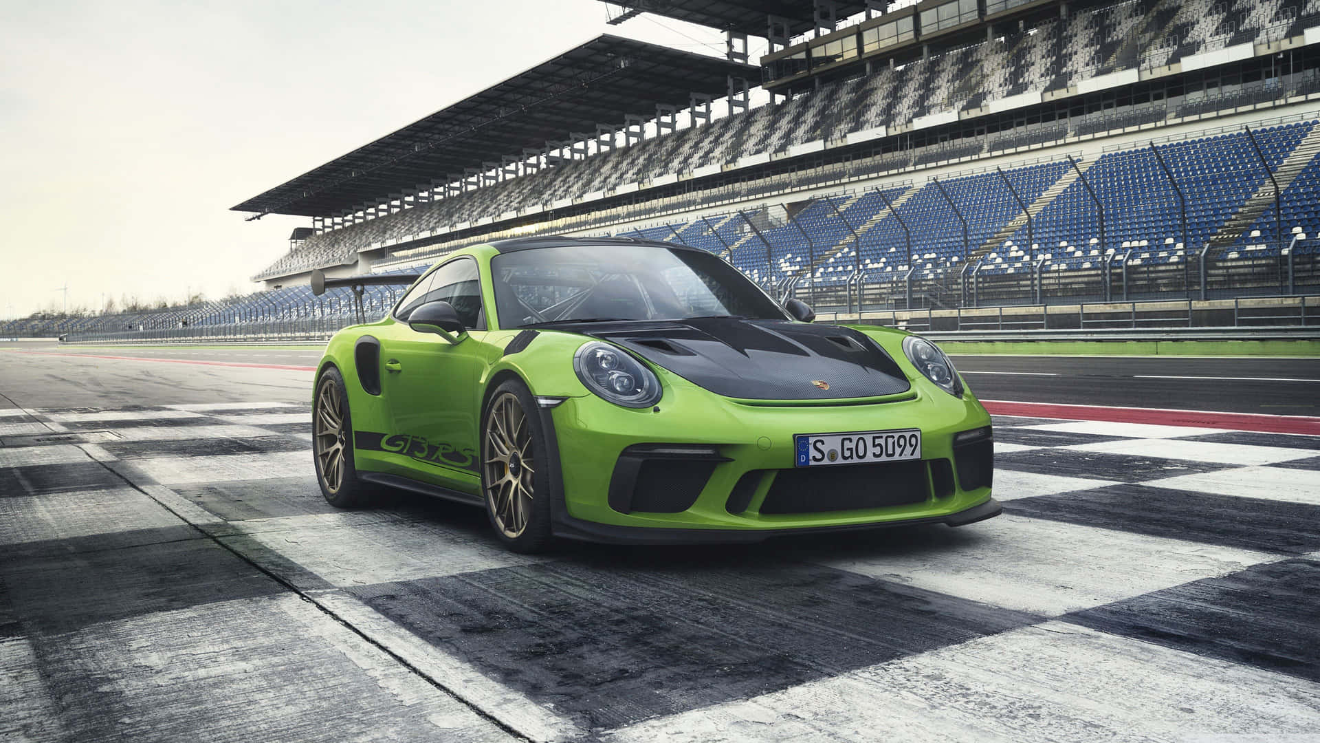  壁紙 — 一輛鮮豔的青檸綠色保時捷911 GT3 RS停在方格賽車道上，背景是空無一人的看台。