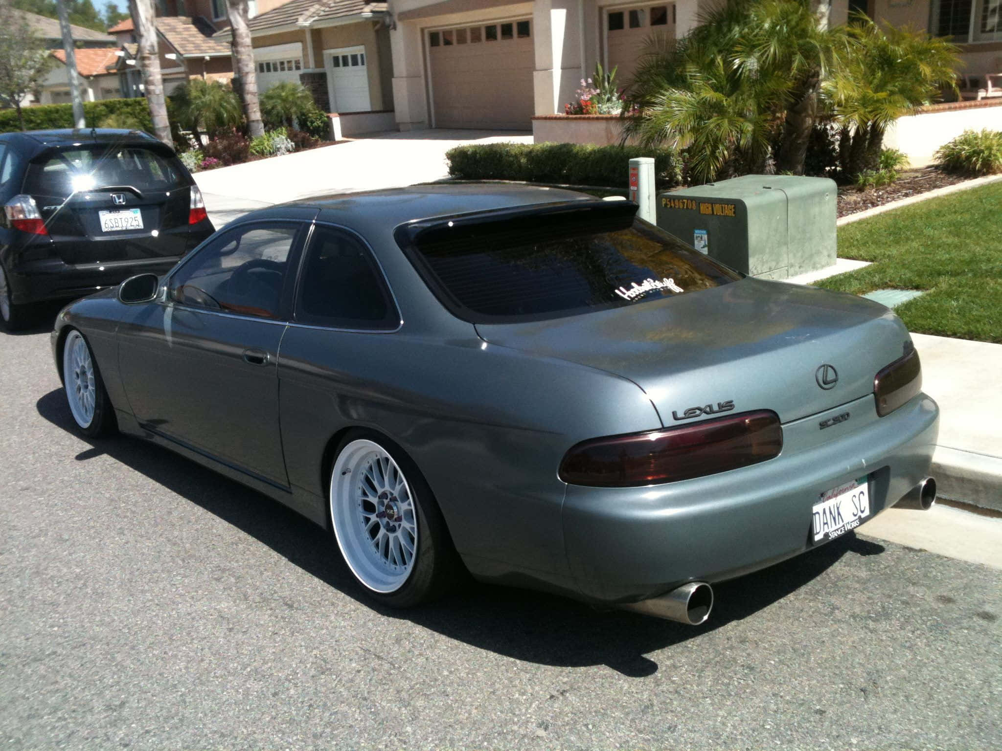 Lexus Sc 300 桌布 壁紙 — 一輛消光灰色的 Lexus SC300 運動型轎跑車，配備定制白色輪圈，停放在陽光明媚的郊區街道上。