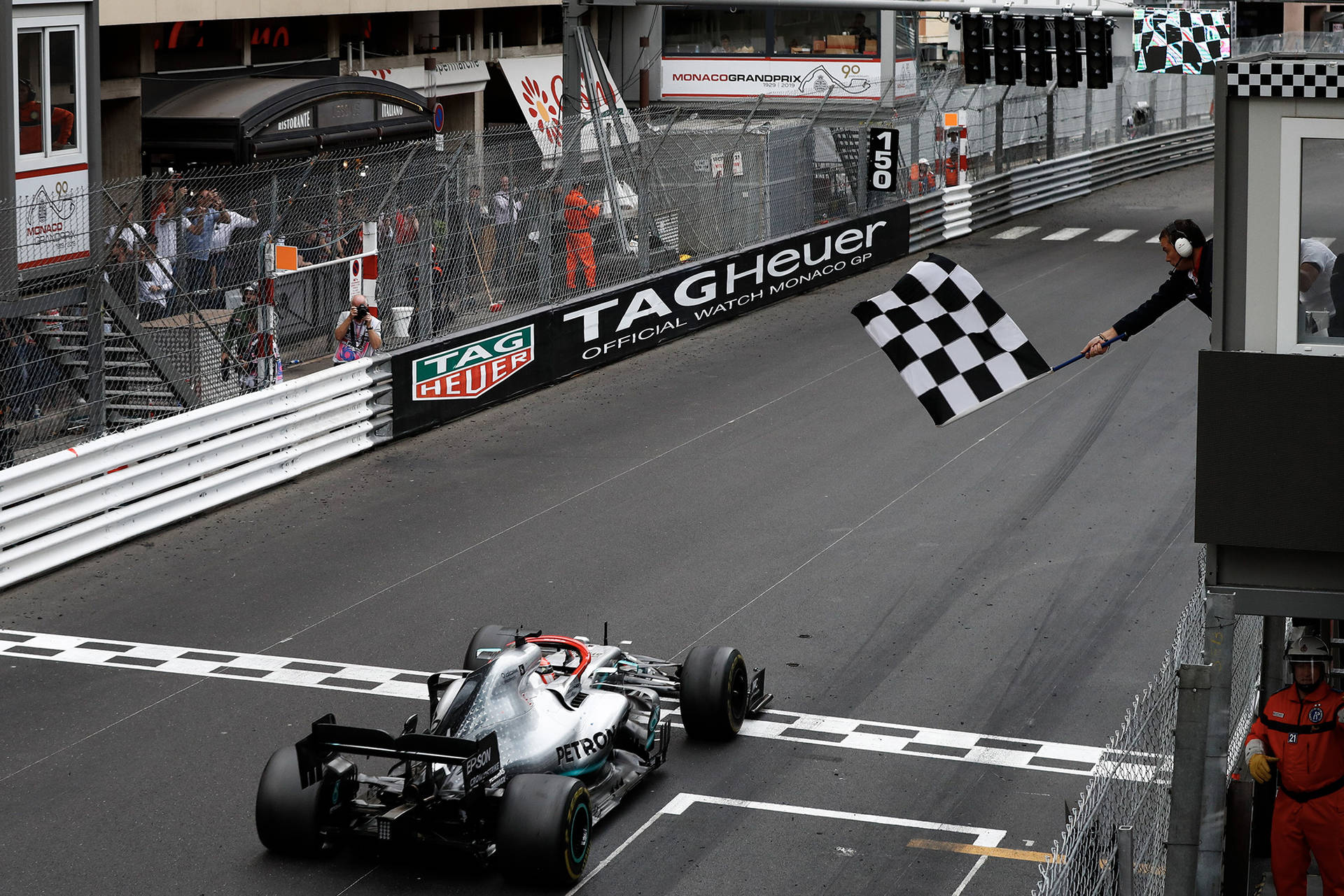 一級方程式賽車越過終點線，工作人員揮舞方格旗。 — F1 壁紙