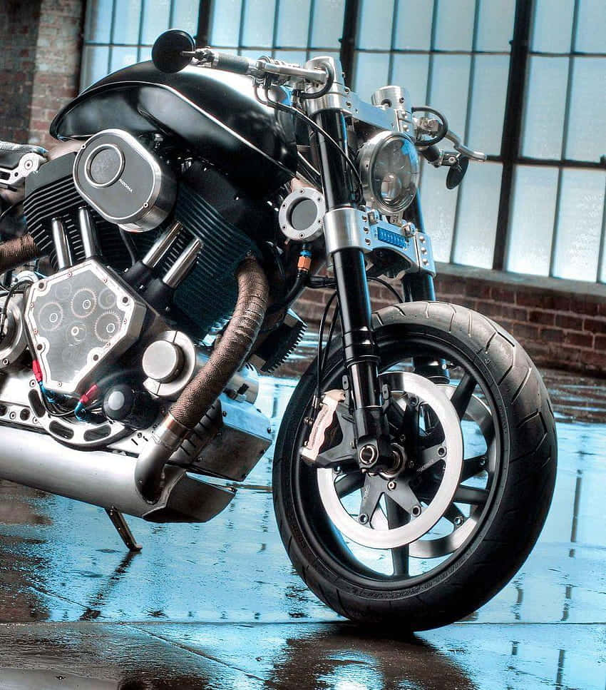 Confederate Motorcycle 桌布 壁紙 — 一輛帶有鍍鉻裝飾的定制黑色摩托車停在大工業窗戶下的濕瀝青路面上。