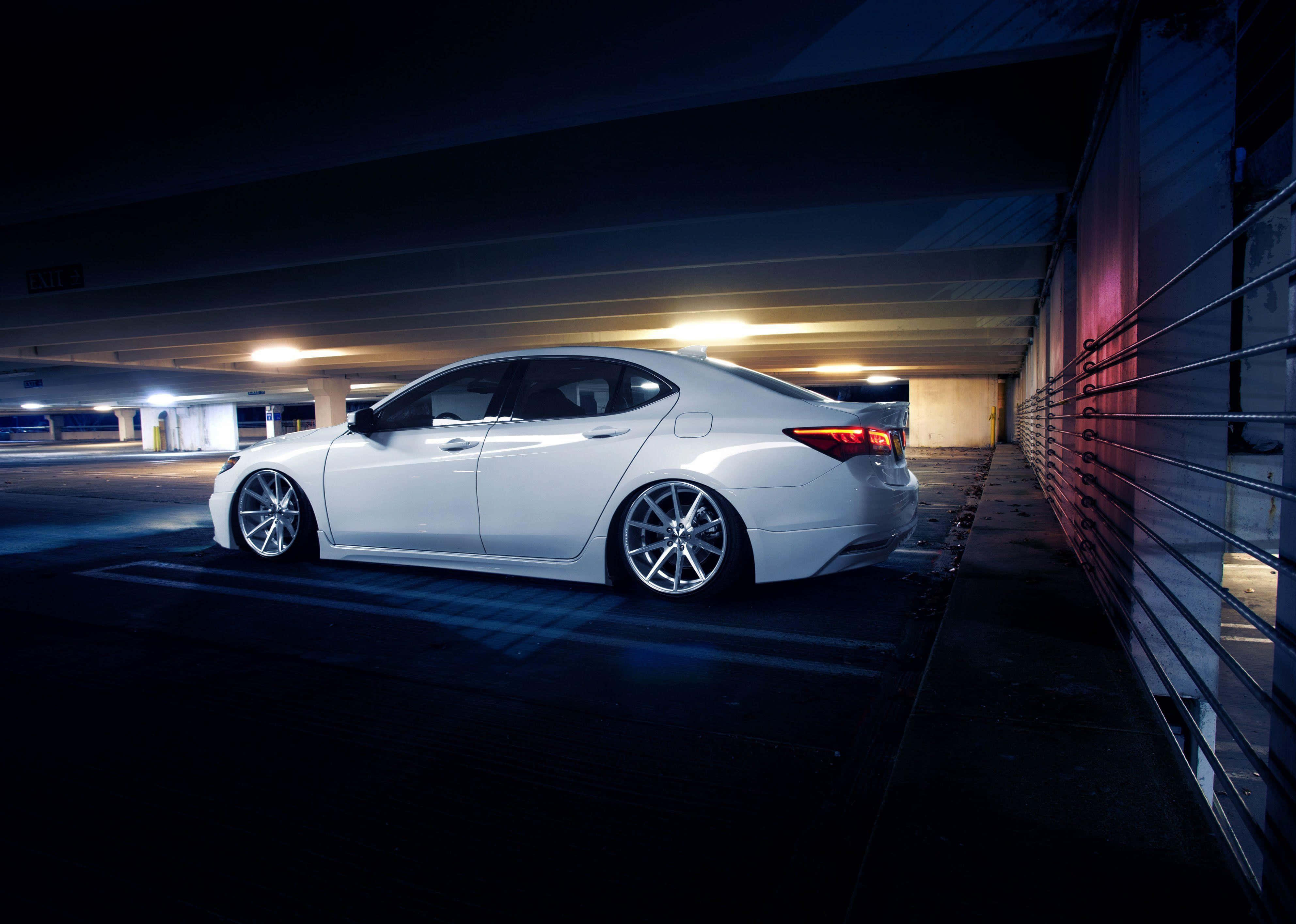 Acura Tlx 桌布 壁紙 — 一輛時尚的白色轎車停泊在燈光昏暗的城市高架橋下，發光的燈光在潮濕的路面上投射出倒影。