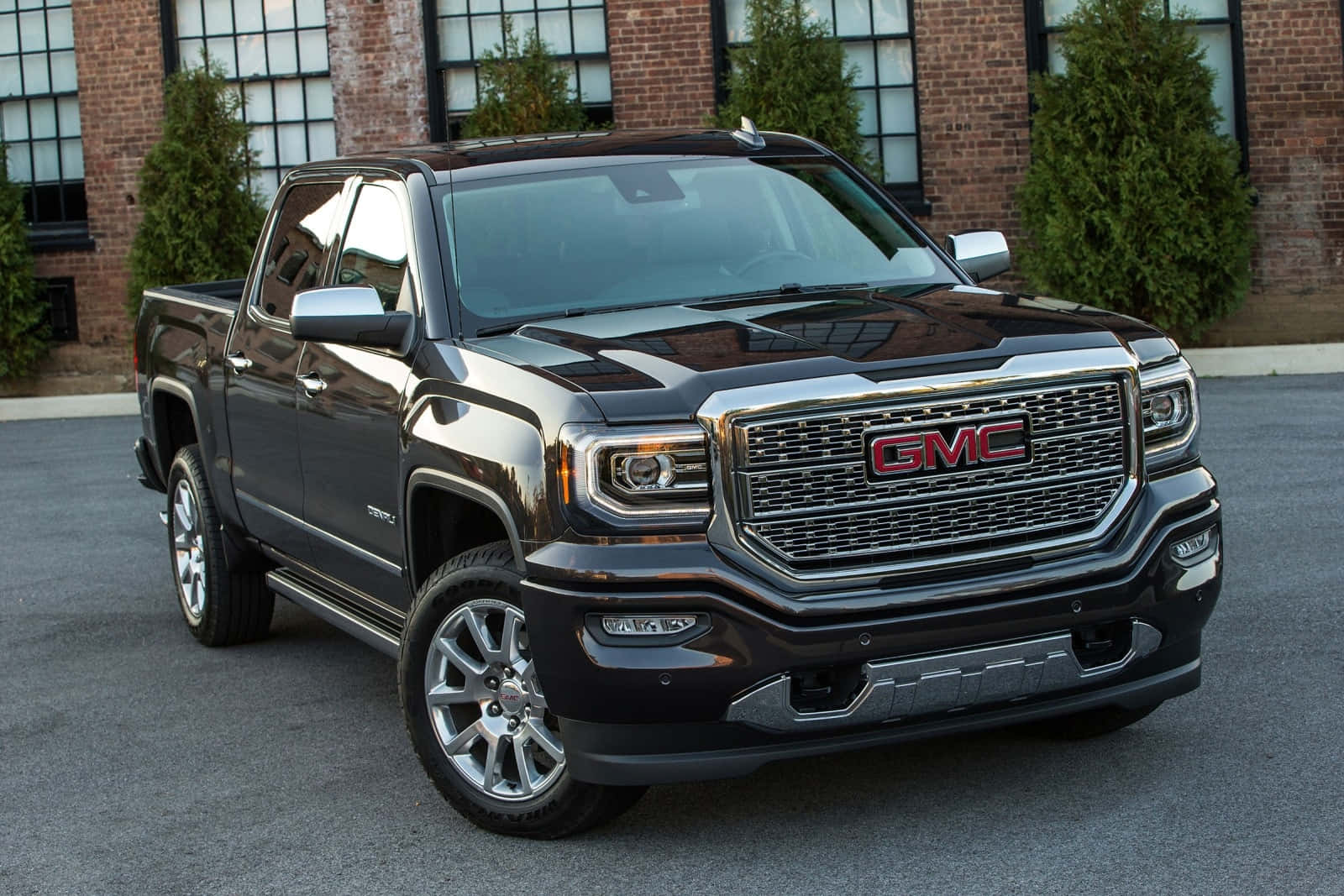 Gmc Sierra 桌布 壁紙 — 一輛時尚的黑色GMC Sierra皮卡車停在磚造建築前瀝青路面上，建築物有大窗戶。