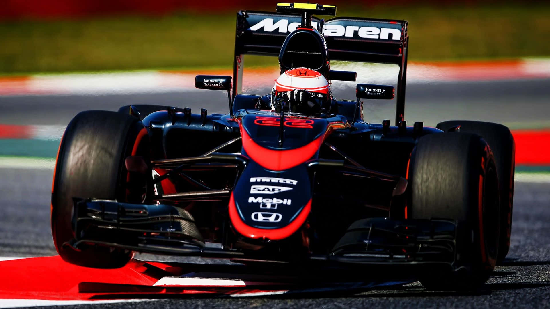 Mclaren F1 桌布 壁紙 — 一輛時尚的黑色和紅色麥拉倫一級方程式賽車在賽道上疾馳，車手戴著紅白頭盔。