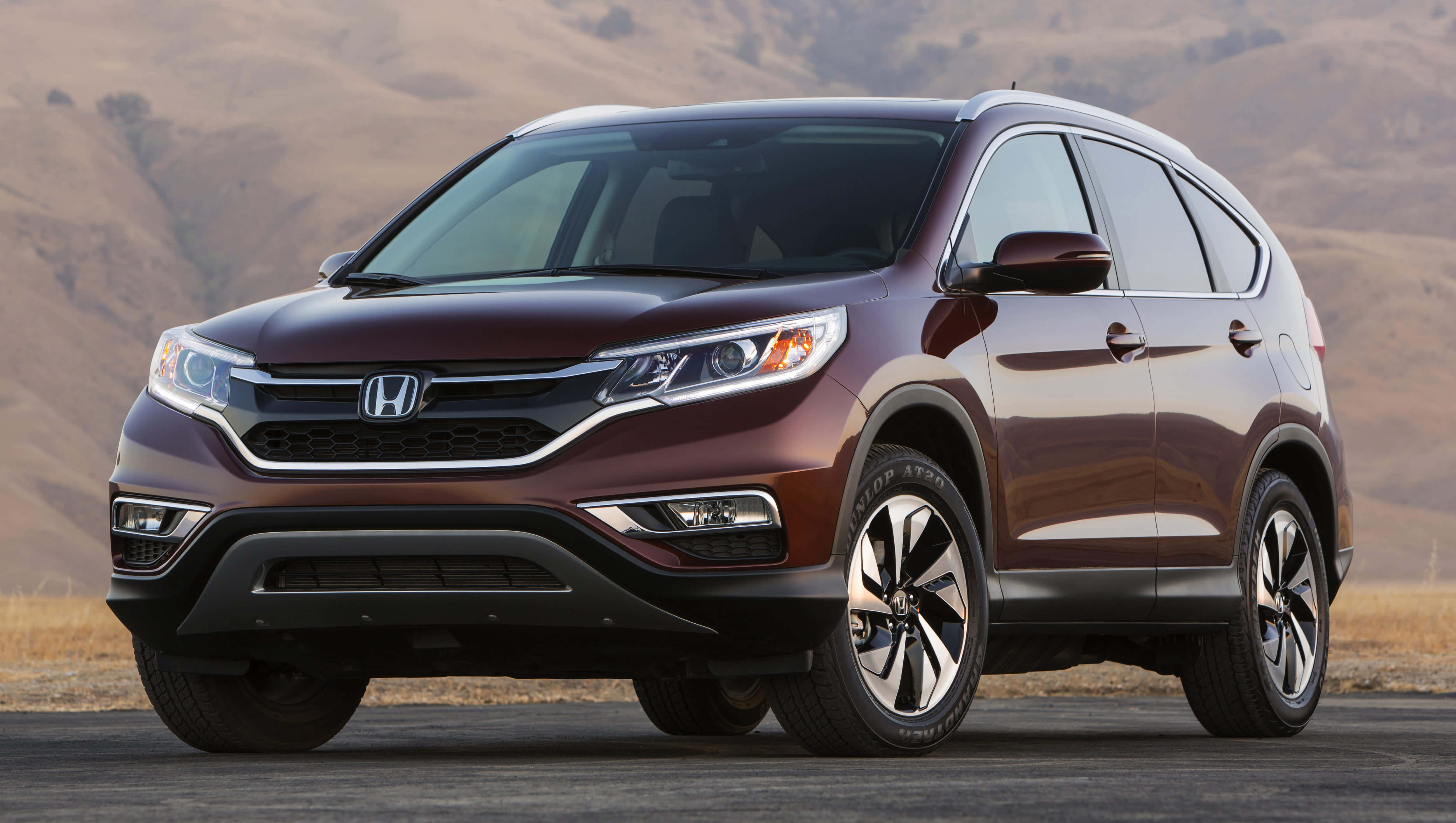 Honda Cr-v 桌布 壁紙 — 一輛時尚的酒紅色本田CR-V SUV在明亮的日光下停泊在瀝青路上，背景是乾燥的山丘。