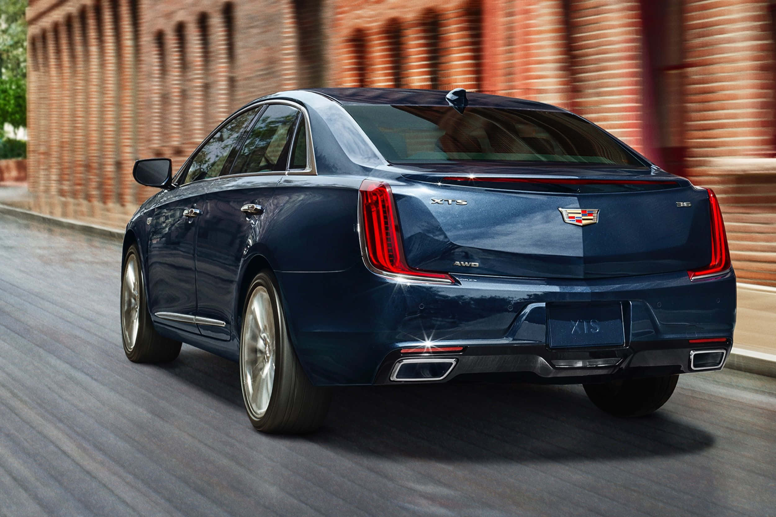 Cadillac Xts 桌布 壁紙 — 一輛時尚的藍色凱迪拉克XT5 SUV在城市的街道上行駛，經過紅磚牆，帶有動態模糊效果。