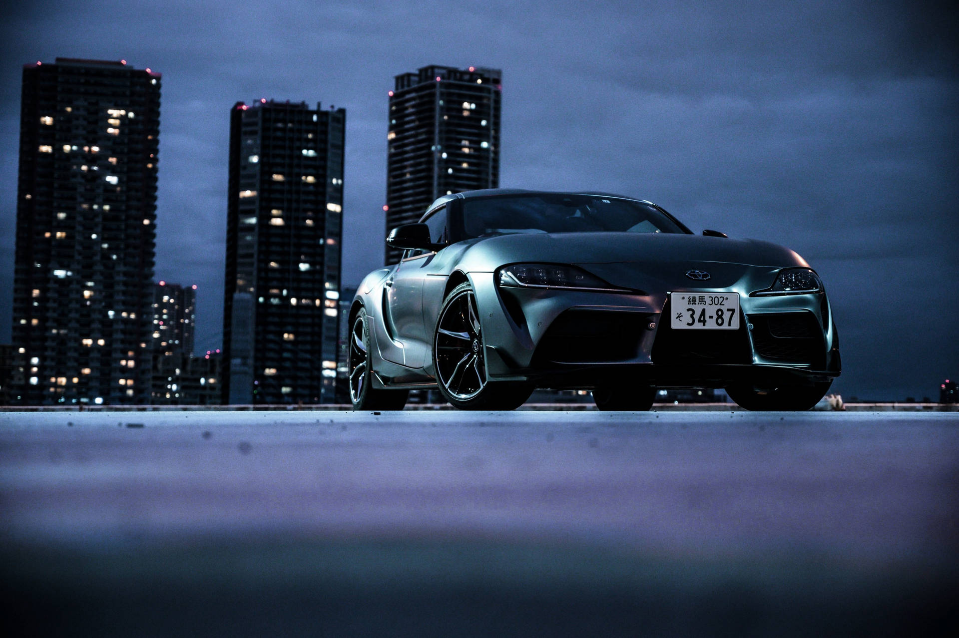 黃昏時屋頂上的銀色跑車，以城市天際線為背景。 — Toyota Supra 壁紙