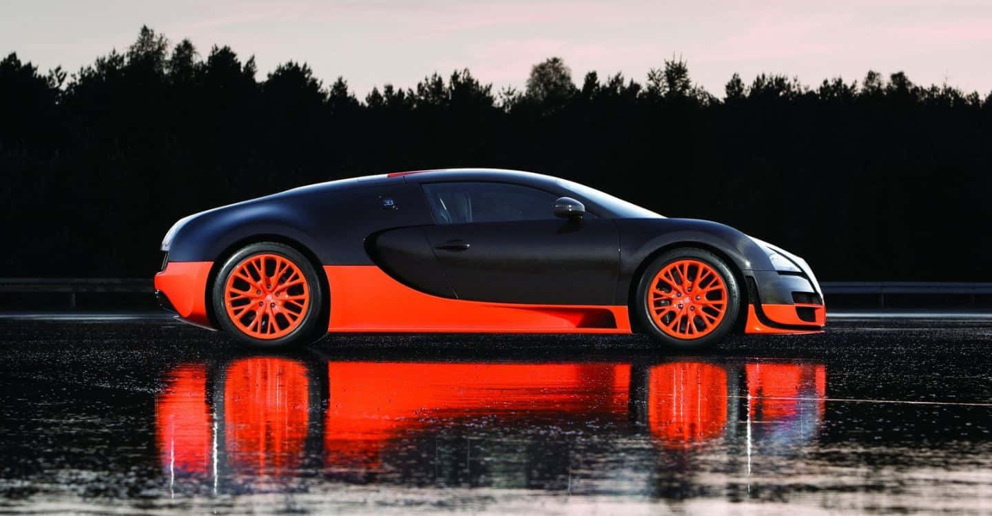Bugatti Veyron 桌布 壁紙 — 一輛時尚的黑色和橙色Bugatti跑車在黃昏時分，在濕漉漉的柏油路面上，映襯著黑暗的森林，倒影清晰可見。