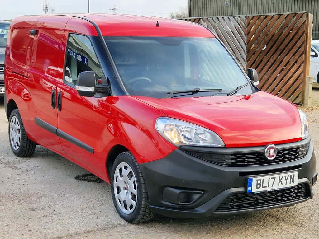  壁紙 — 一輛鮮紅色的菲亞特 Fiorino 客貨車停在碎石上，背景有木柵欄。
