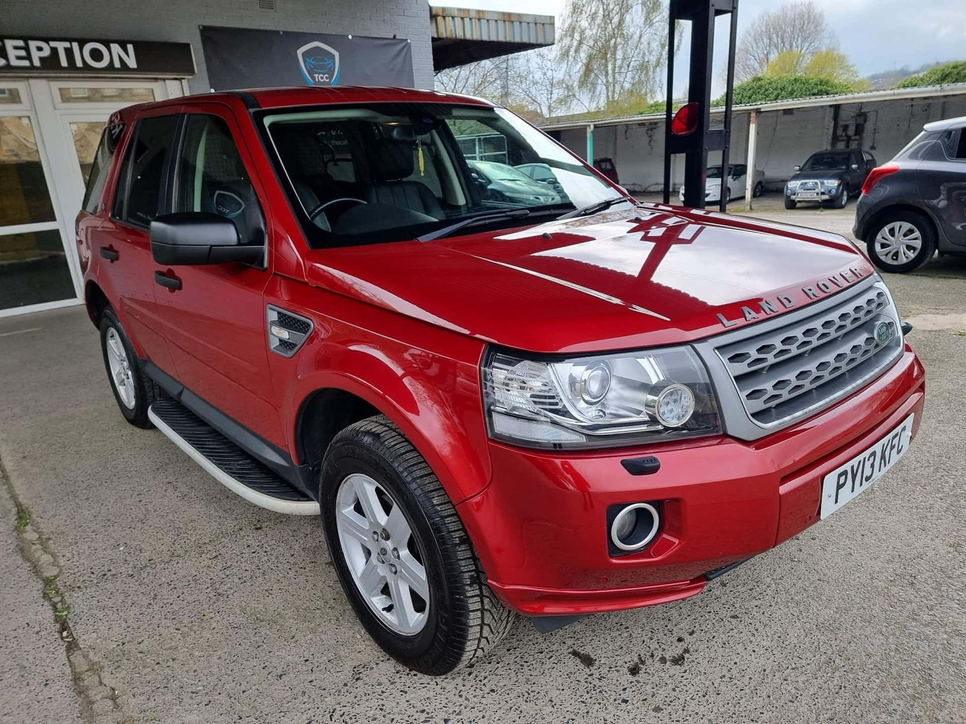 Land Rover Freelander 桌布 壁紙 — 一輛光亮的紅色 Land Rover Freelander 停放在經銷商外，背景可見其他車輛。