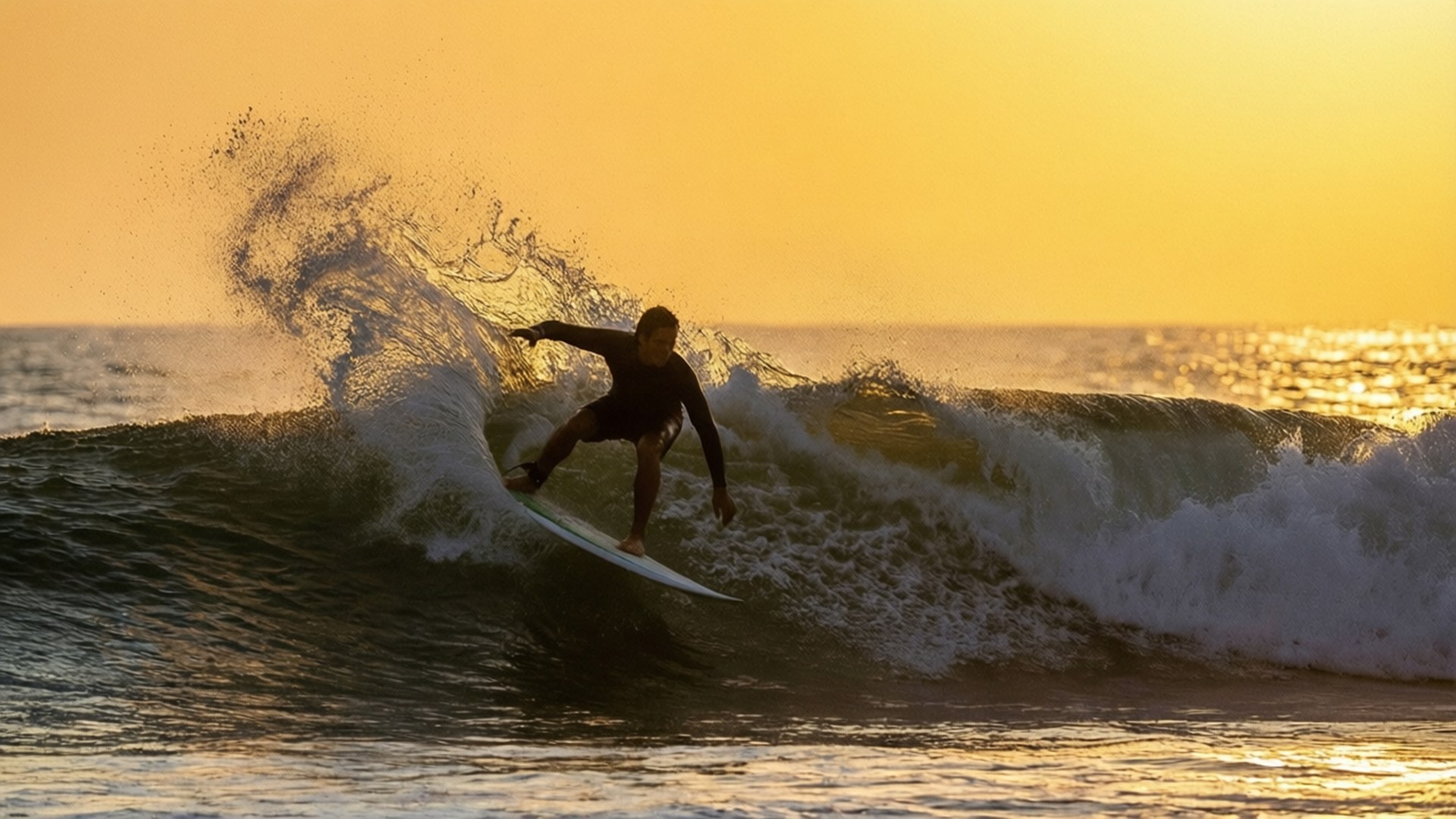 Puerto Escondido Sunset Surf 壁紙 — 一名衝浪者在日落時分乘著破碎的波浪，金色的光芒照亮了水花和海洋。