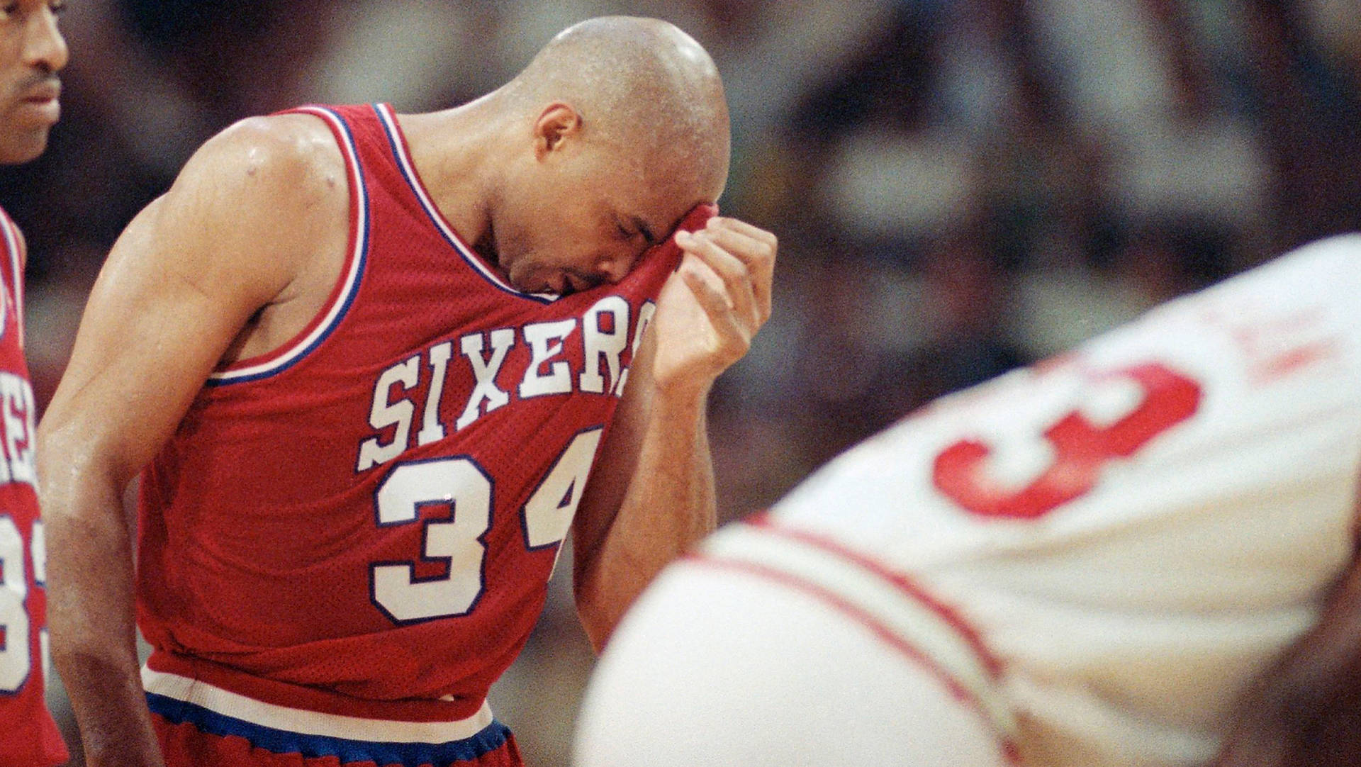 身穿紅色Sixers球衣的籃球運動員賽後用球衣擦臉。 — NBA 壁紙