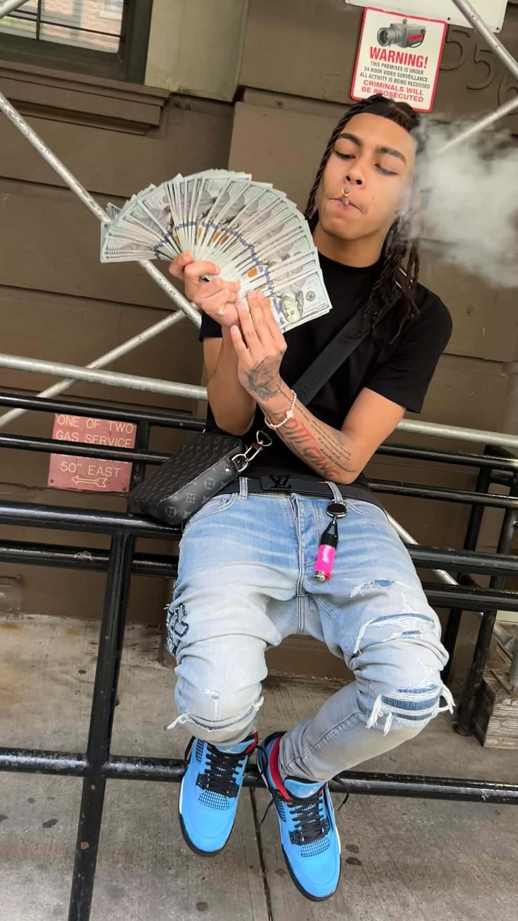  壁紙 — 一名留著辮子的年輕男子坐在長椅上，手持一疊現鈔，同時從電子煙中呼出煙霧。
