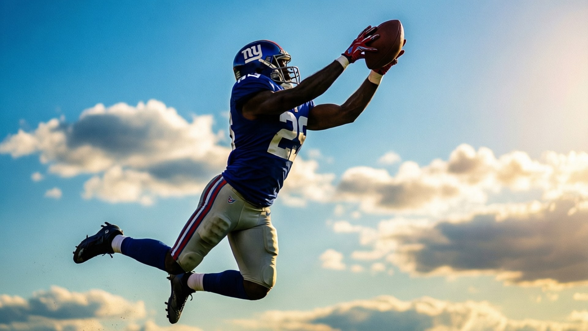 Giants Catch Silhouette 壁紙 — 一名紐約巨人隊美式足球員在金色夕陽天空下高高躍起，用雙手接住一個美式足球。