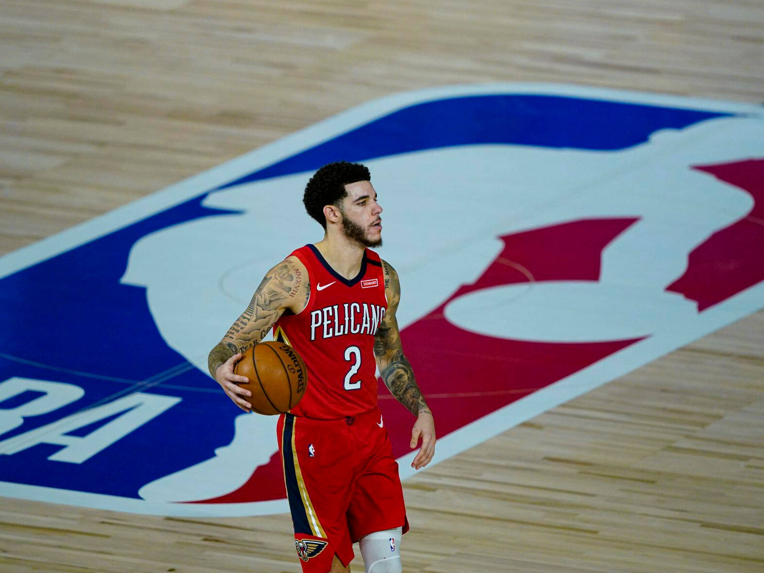 身穿紅色Pelicans球衣的籃球運動員在球場上持球。 — NBA 壁紙