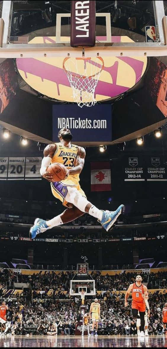 一名身穿湖人球衣的籃球運動員在擠滿觀眾的場館中灌籃。 — King Lebron James 壁紙