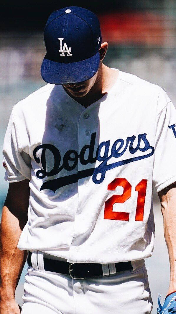 身穿道奇隊球衣背號21號並戴帽子的棒球運動員低頭看著。 — MLB 壁紙