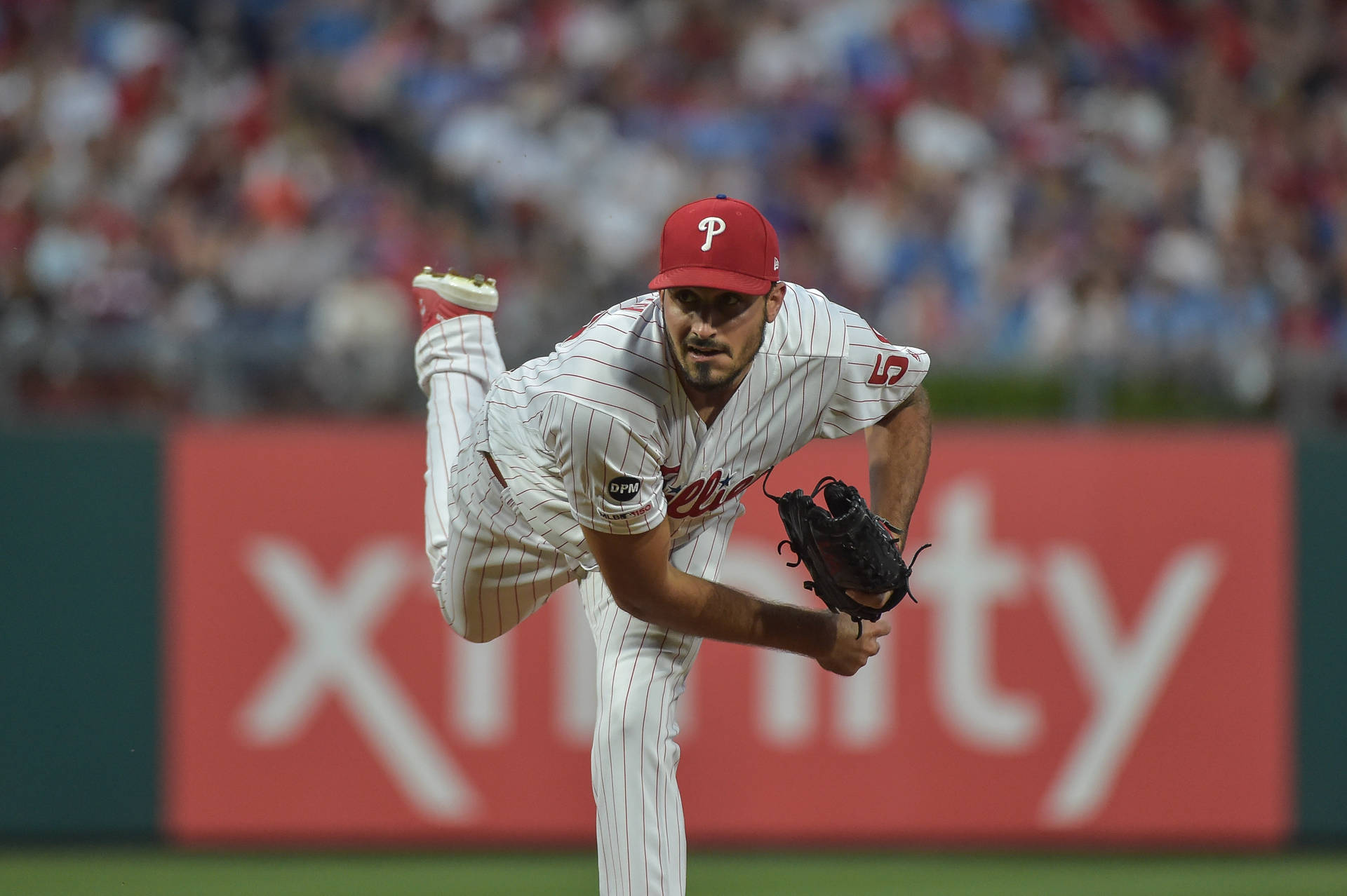 棒球投手在夜間燈光球場上投球，背景有觀眾。 — MLB 壁紙