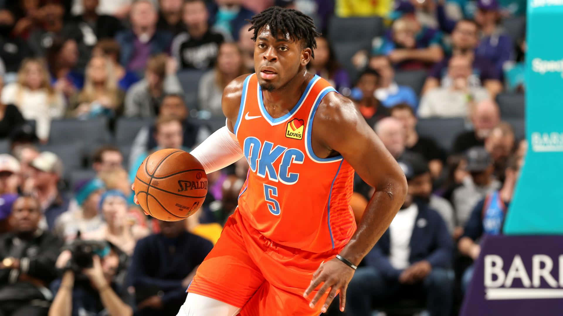 身穿橙色OKC球衣的籃球運動員在比賽中運球。 — NBA 壁紙