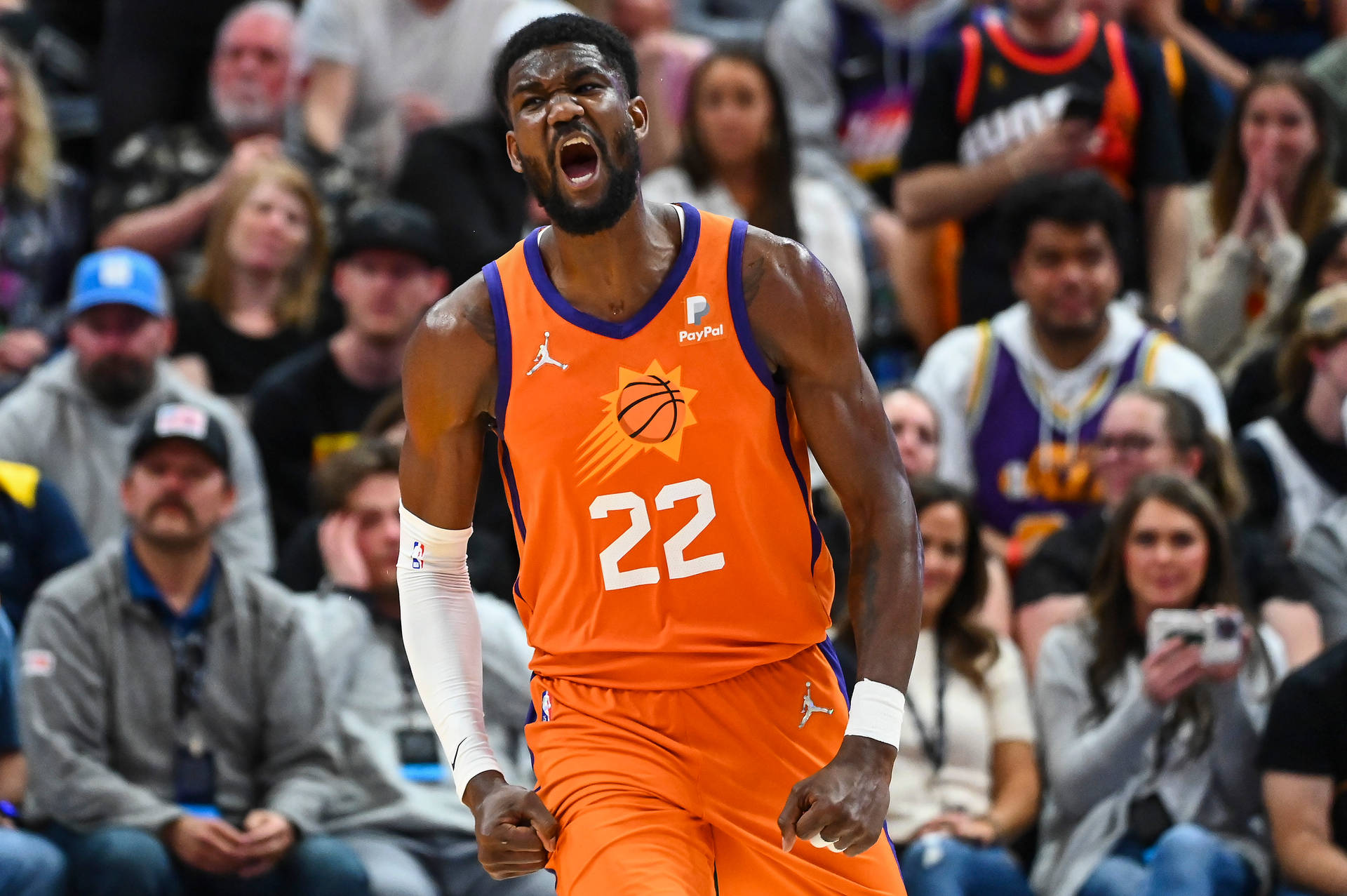 身穿橙色太陽隊球衣的籃球運動員在比賽中對著人群咆哮。 — NBA 壁紙