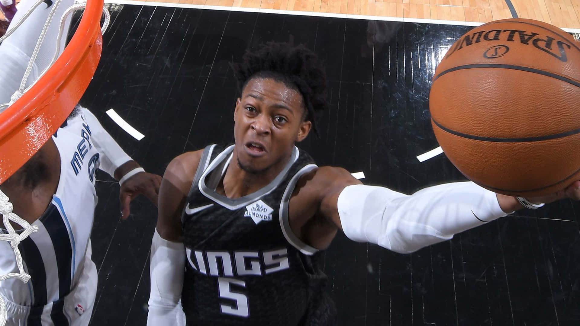 身穿黑色球衣的籃球運動員在比賽中嘗試灌籃。 — NBA 壁紙
