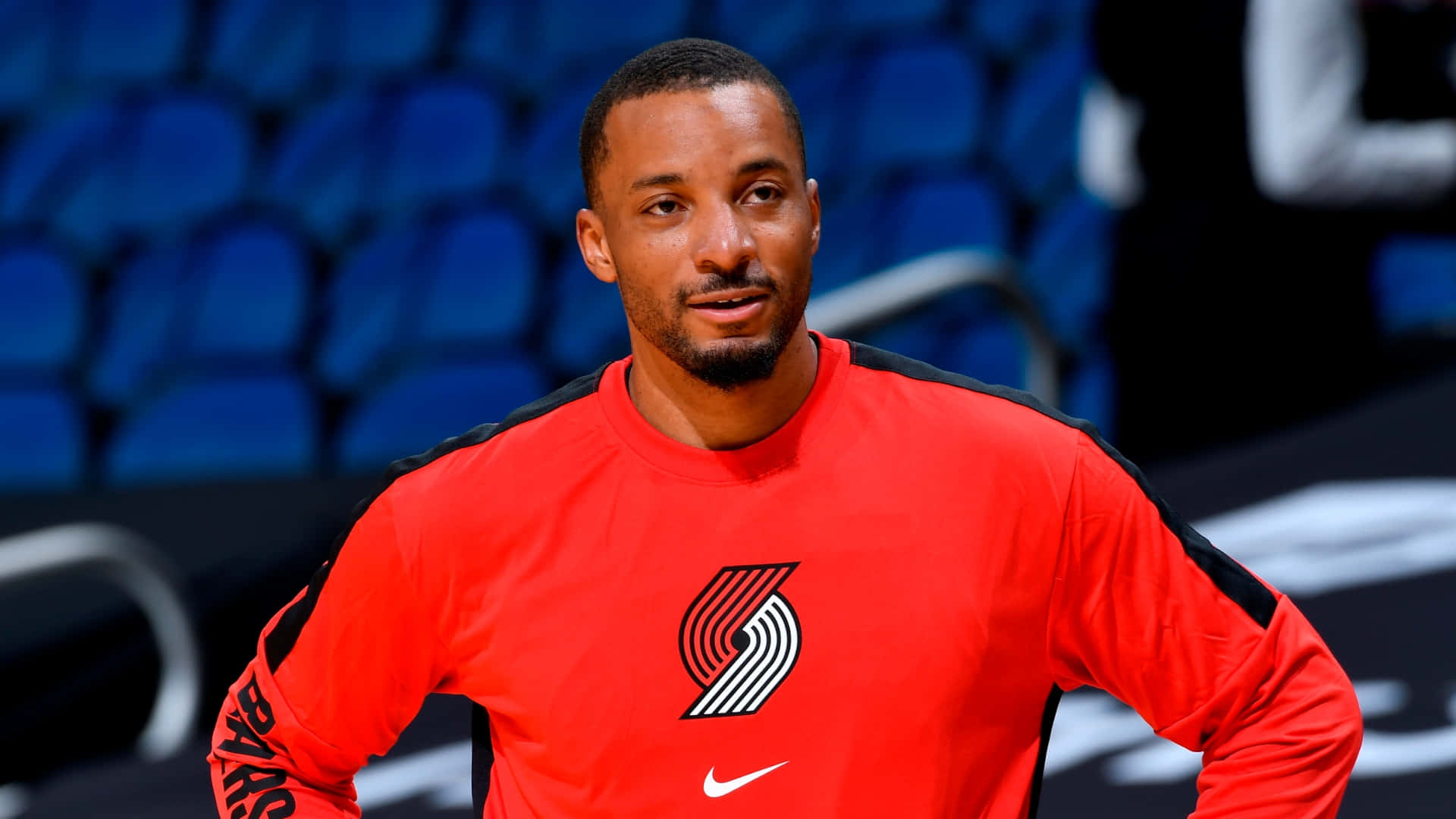 身穿紅色熱身裝備的籃球運動員站在空蕩蕩的球場上。 — NBA 壁紙