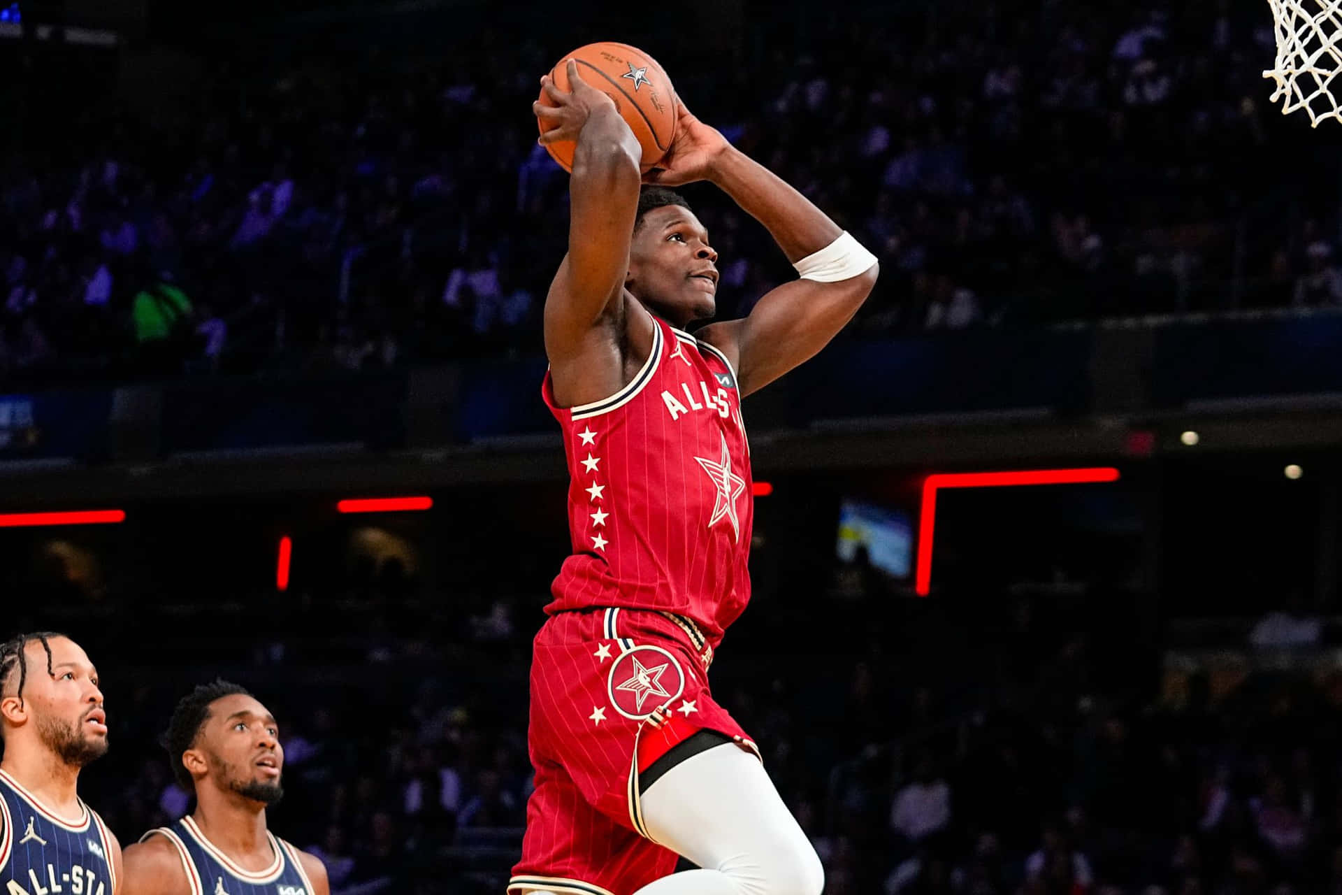 身穿紅色全明星球衣的籃球運動員在場館內灌籃。 — NBA 壁紙