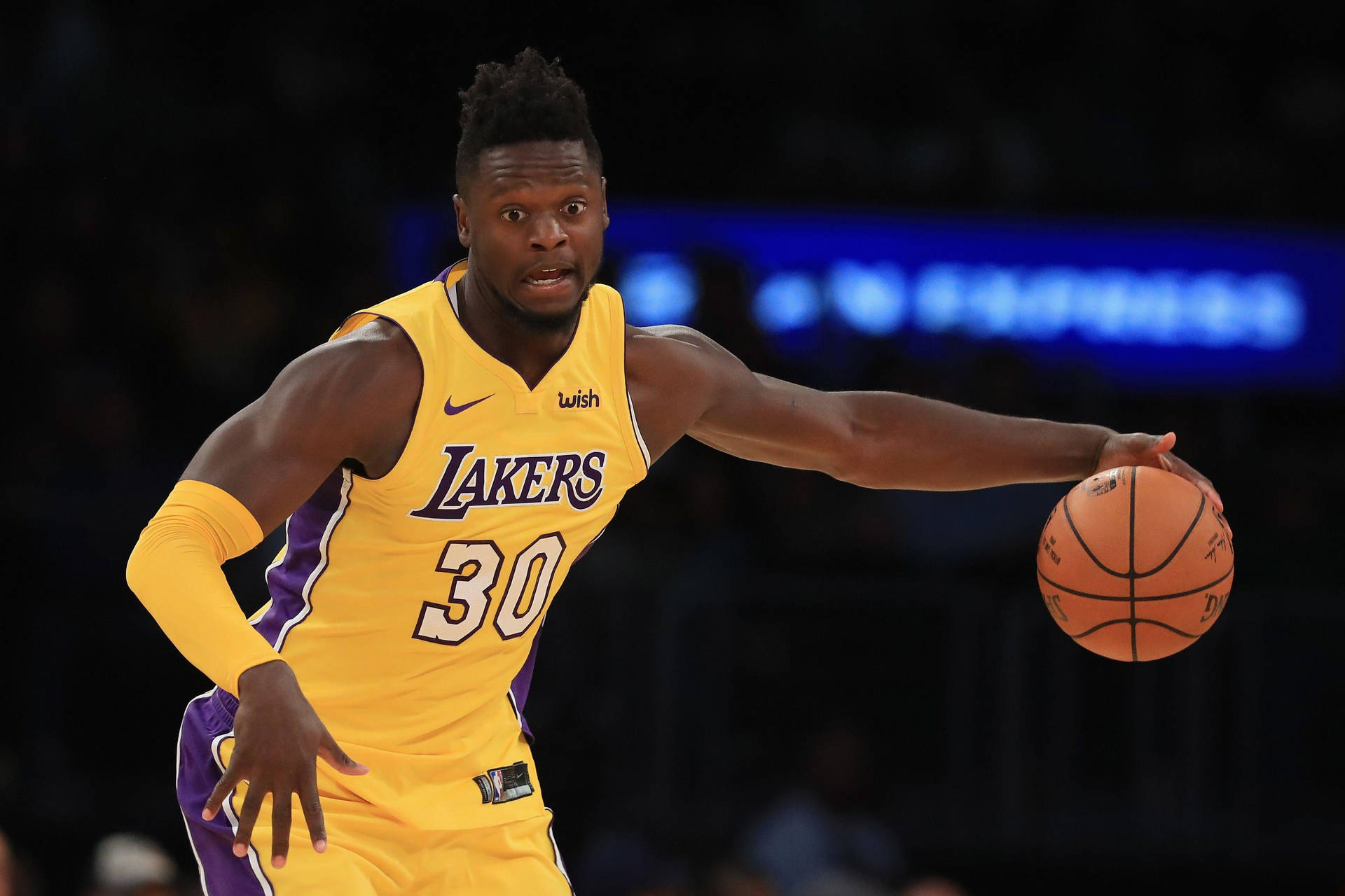 湖人隊籃球運動員在場館燈光下比賽中運球。 — NBA 壁紙