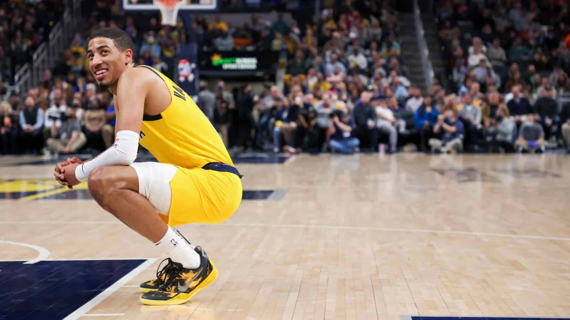 籃球運動員在比賽中蹲在球場上，身後有觀眾。 — NBA 壁紙