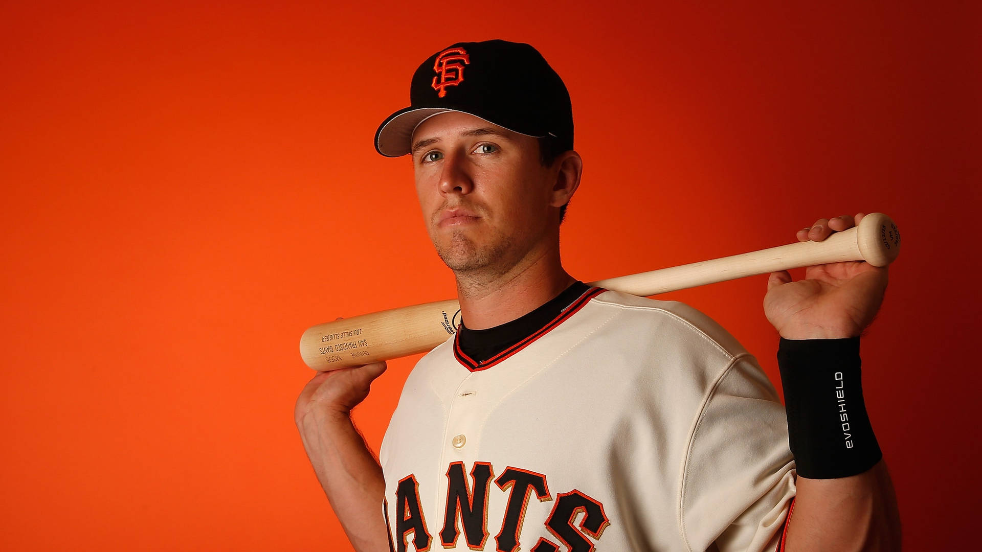 身穿巨人隊球衣的棒球運動員在橙色背景下手持球棒。 — MLB 壁紙