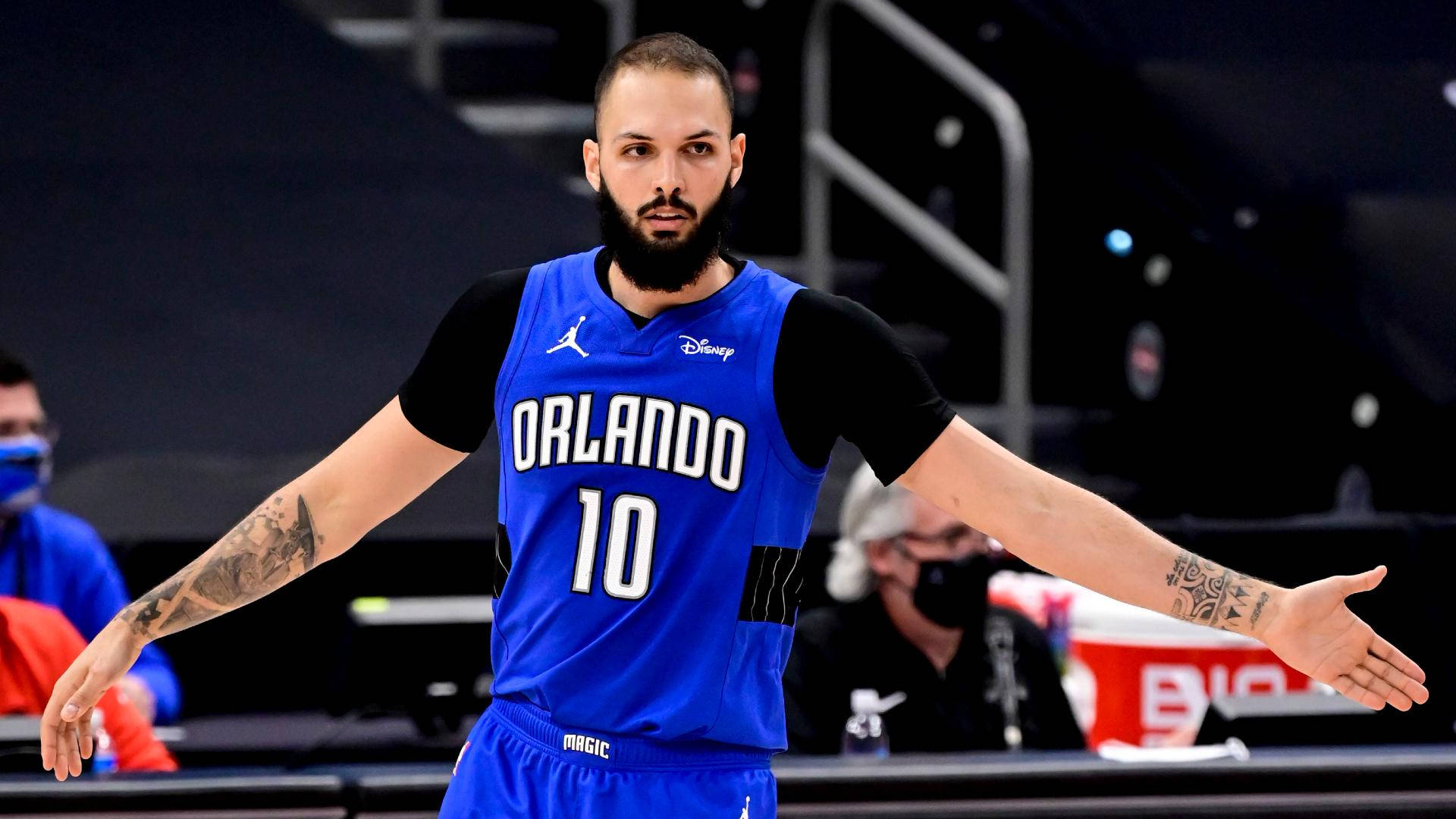 身穿藍色奧蘭多魔術隊球衣的籃球運動員在球場上張開雙臂。 — NBA 壁紙