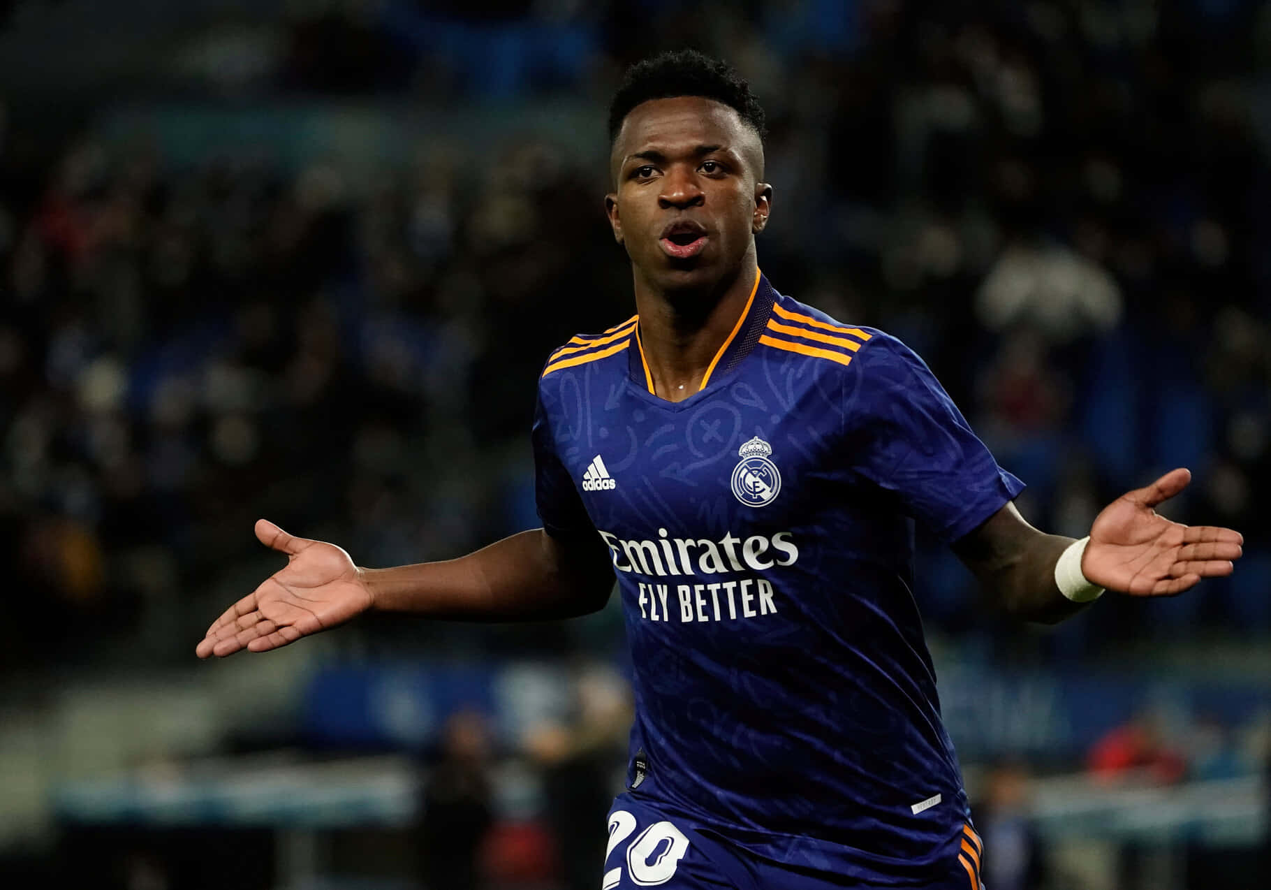  壁紙 — 一名身穿藍色皇家馬德里球衣的足球運動員在夜間比賽中，在球場燈光下驚訝地做手勢。