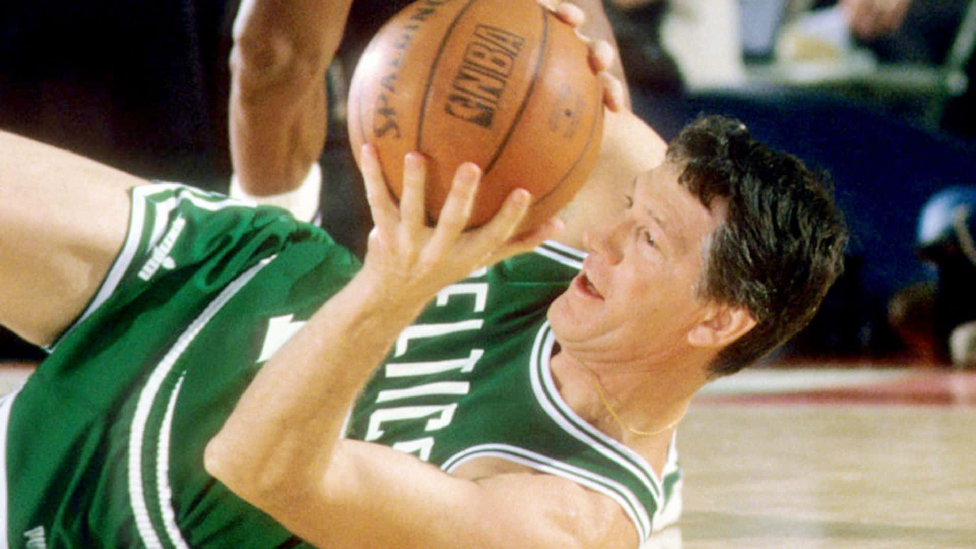 身穿綠色球衣的籃球運動員在比賽中飛身搶籃板。 — NBA 壁紙