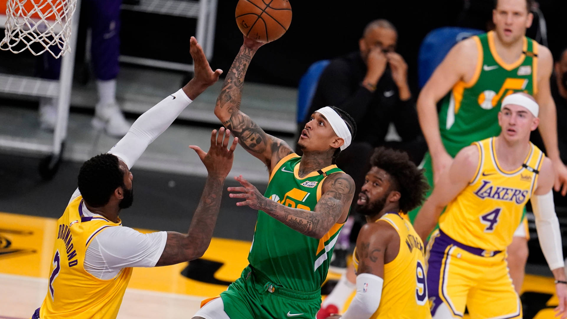 綠色球衣籃球運動員越過黃色防守球員投籃。