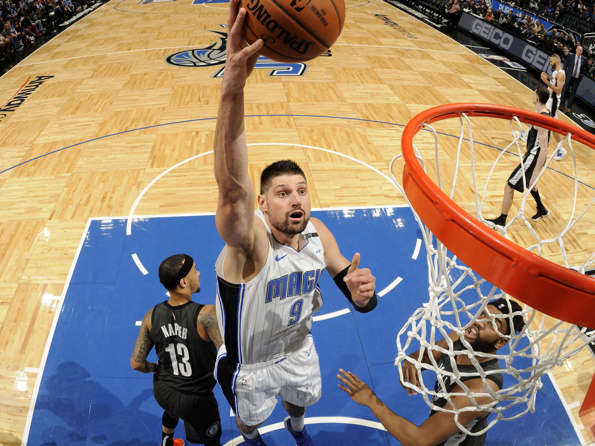 身穿魔術隊球衣的籃球運動員在比賽中灌籃。 — NBA 壁紙