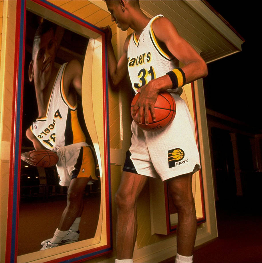 身穿Pacers球衣的籃球運動員在夜晚靠近扭曲的鏡子拿著球。 — NBA 壁紙