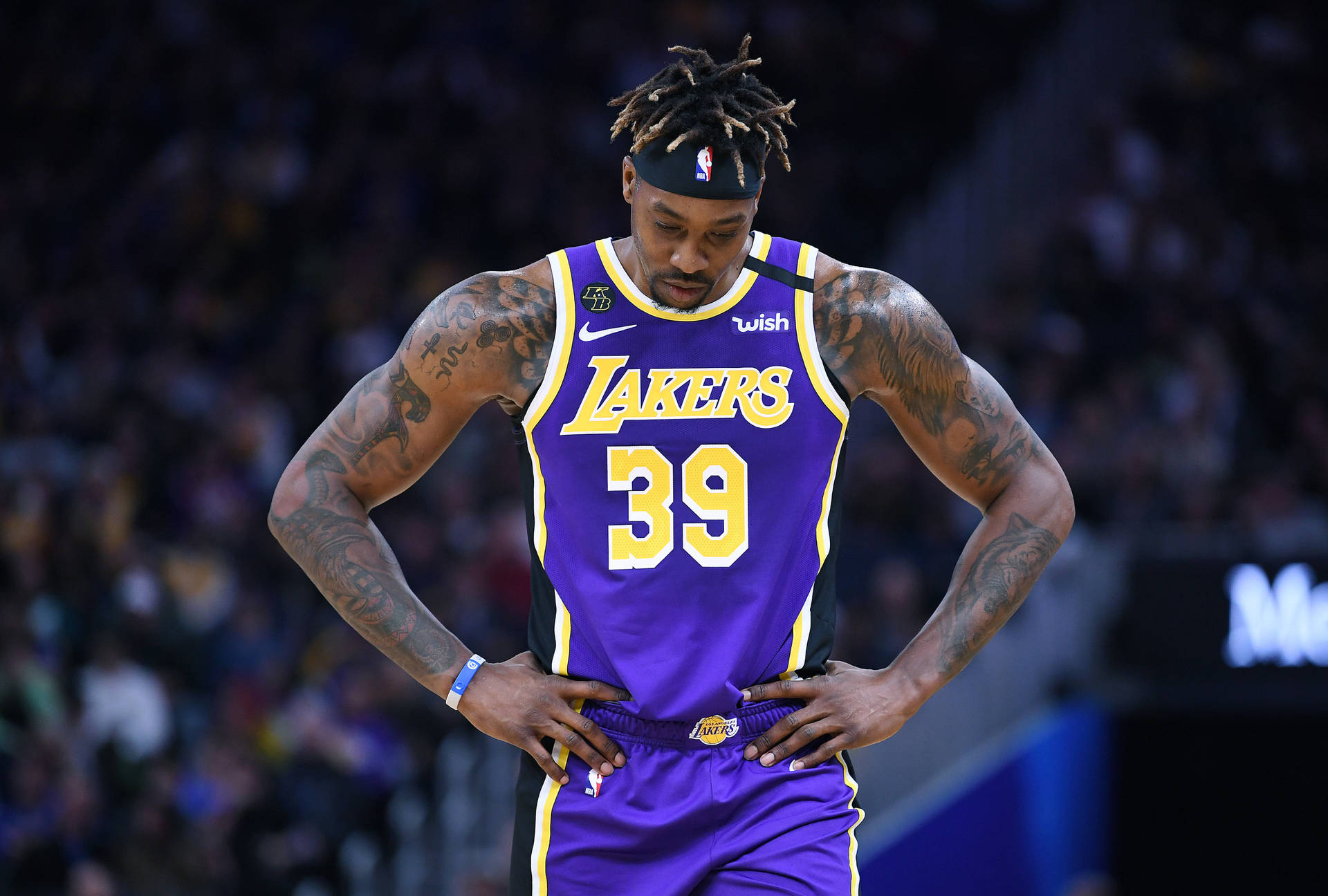 身穿湖人隊球衣的籃球運動員在比賽中雙手叉腰站立。 — NBA 壁紙